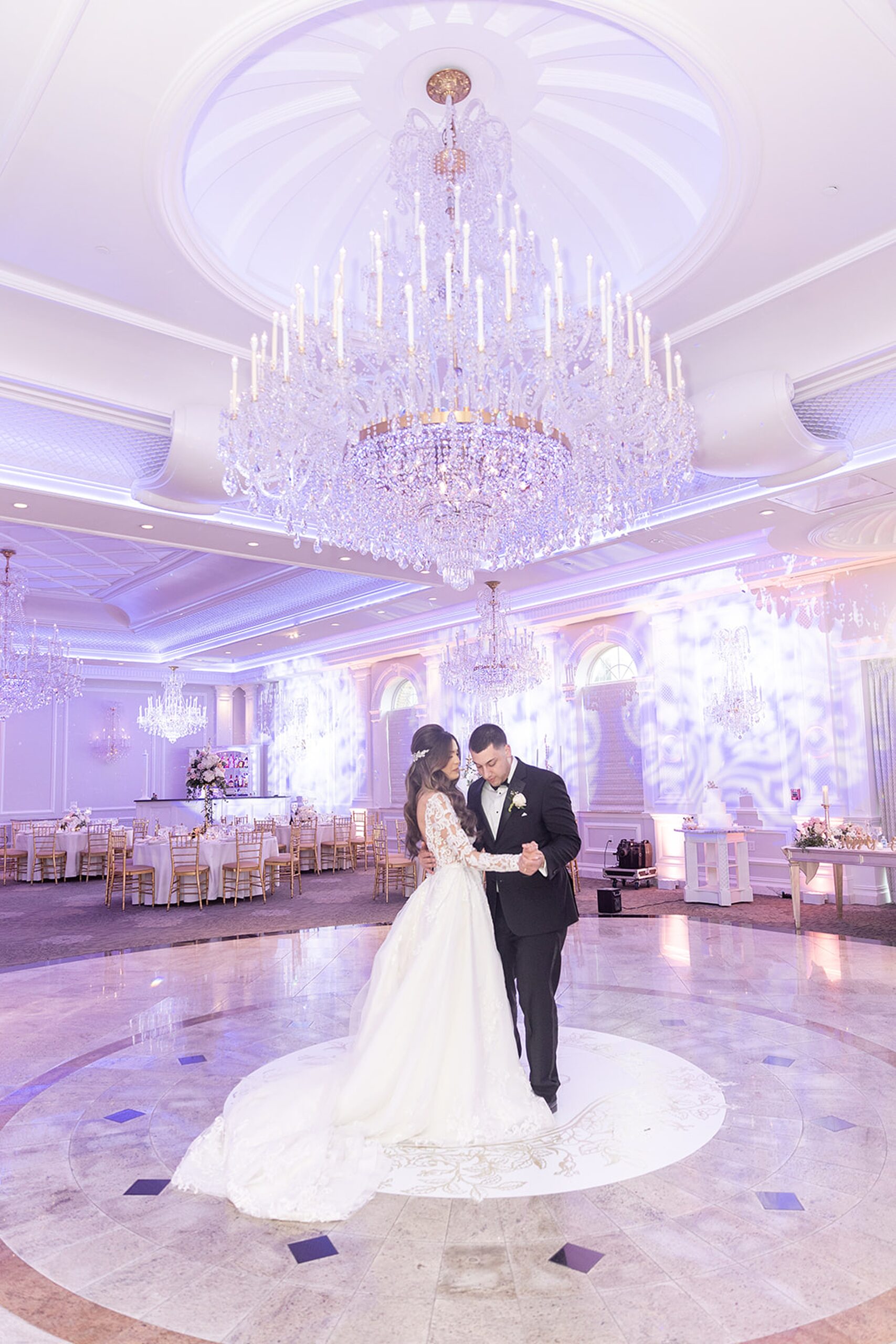 Newlyweds dance in an empty ballroom with large crystal chandeliers before their reception at the rockleigh wedding venue
