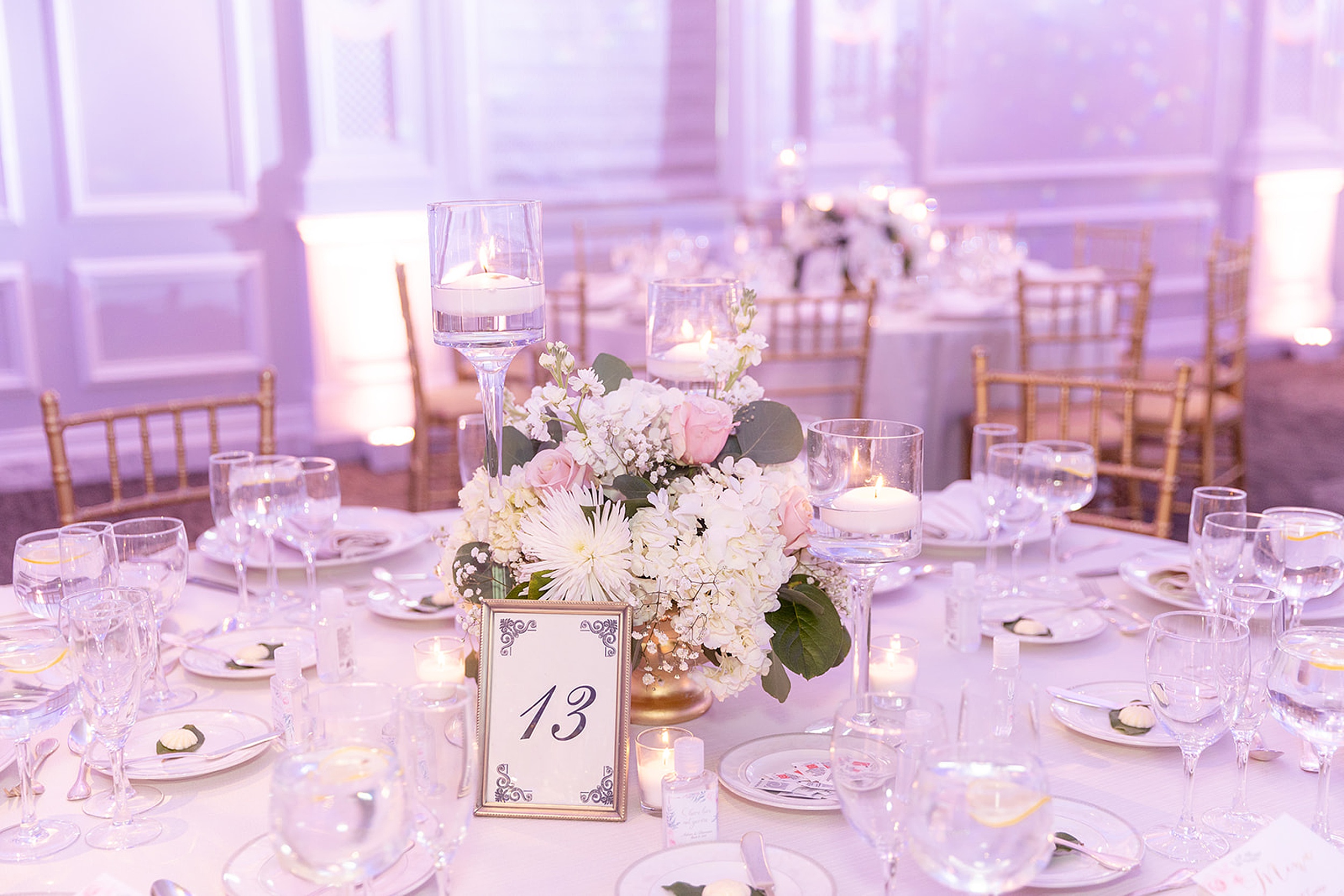 Details of a round table setting with a white and pink flower centerpiece