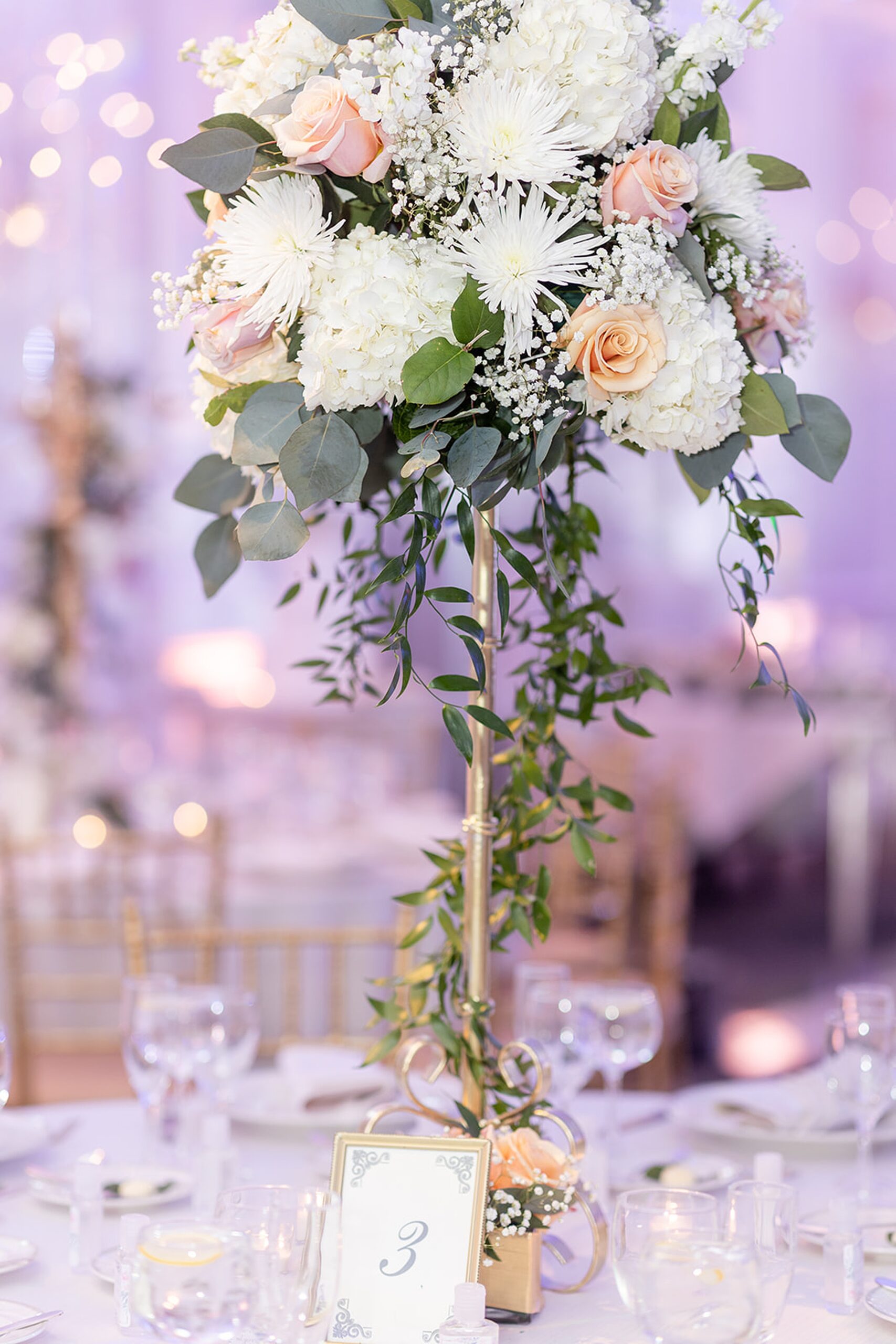 Details of a table setting and tall white flower centerpiece at a wedding reception