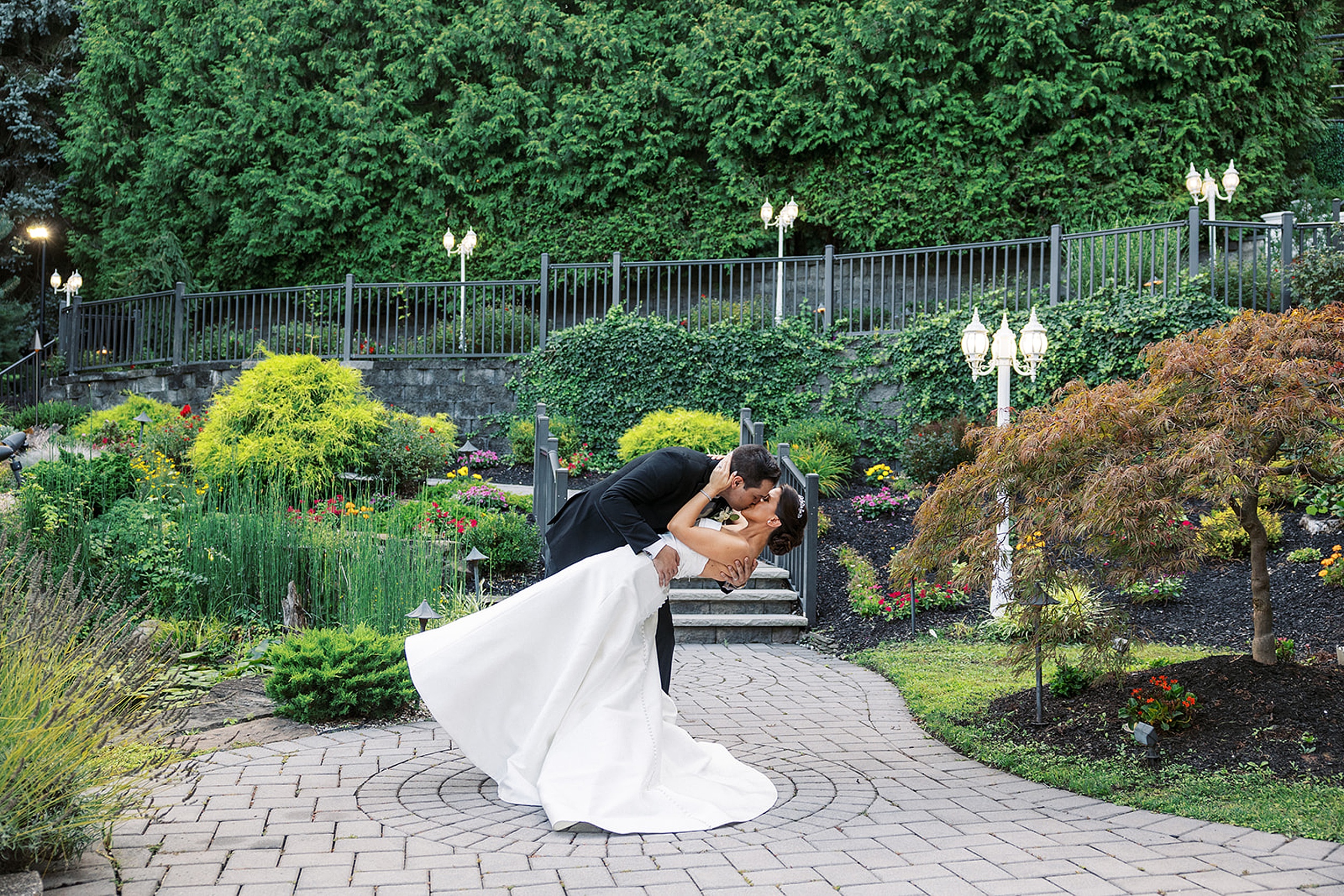 A groom dips and kisses his bride in a garden path at a valley regency wedding