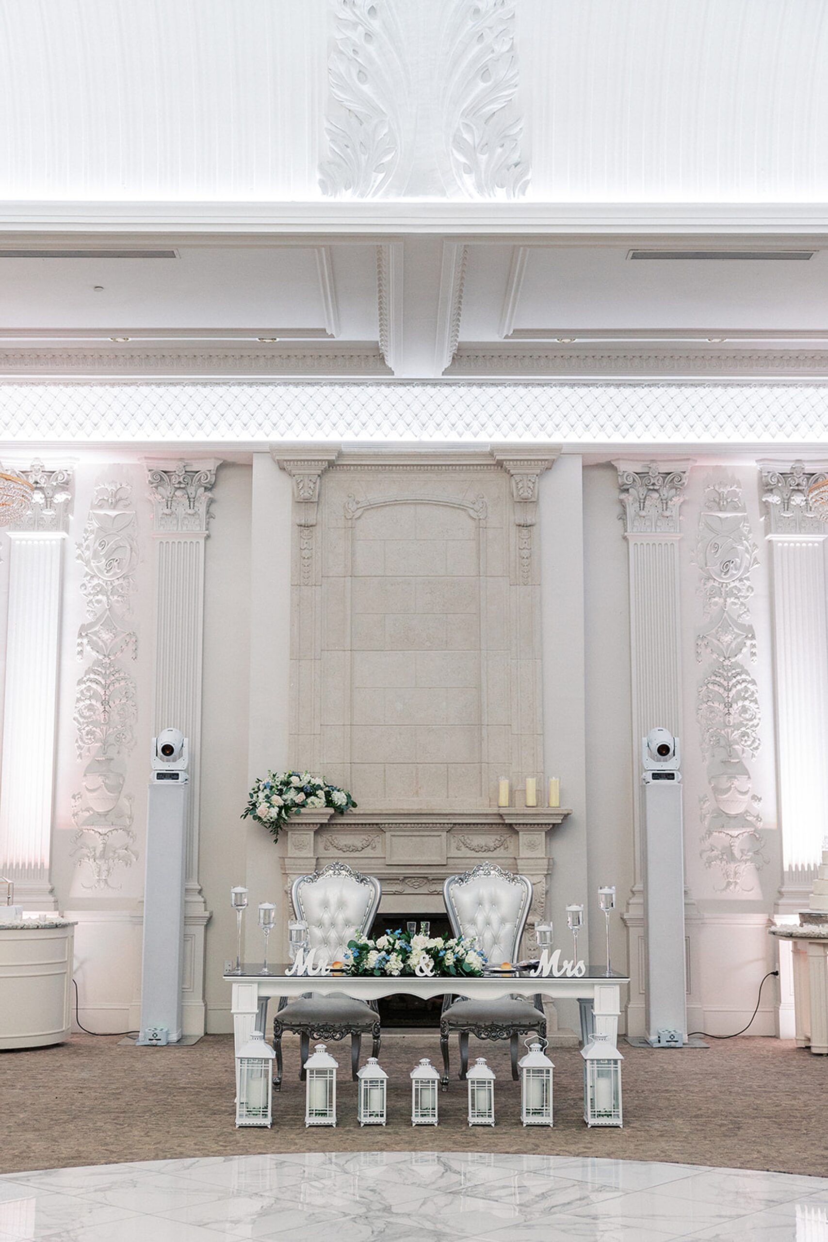 Details of a newlyweds table set up in front of an ornate fireplace with large silver chairs at a valley regency wedding