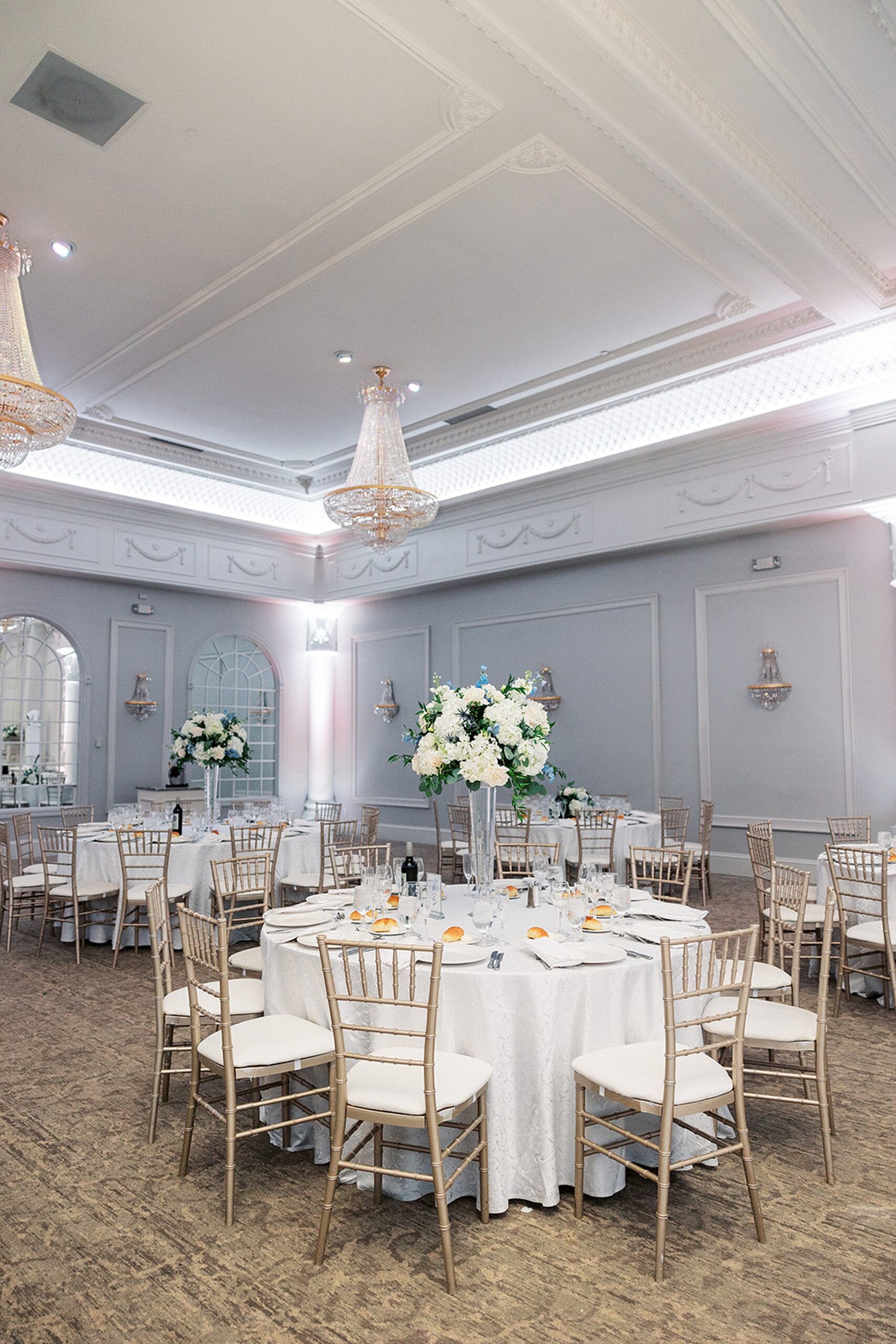 Details of a wedding reception set up in a grand ballroom with crystal chendeliers