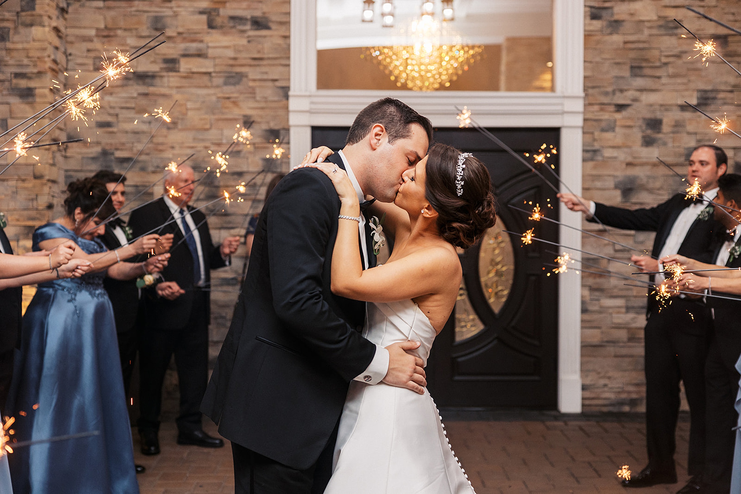 Newlyweds kiss while surrounded by their guests holding sparklers over them at a valley regency wedding