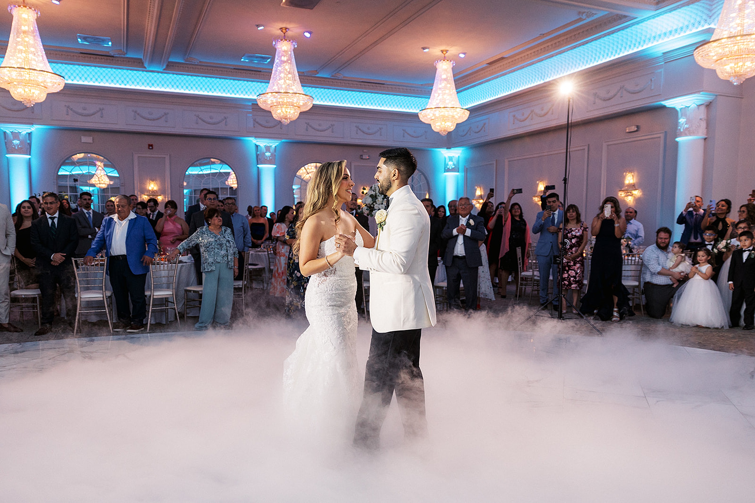 Newlyweds dance on a dance floor covered in ground fog and surrounded by crystal chandeliers at a valley regency wedding