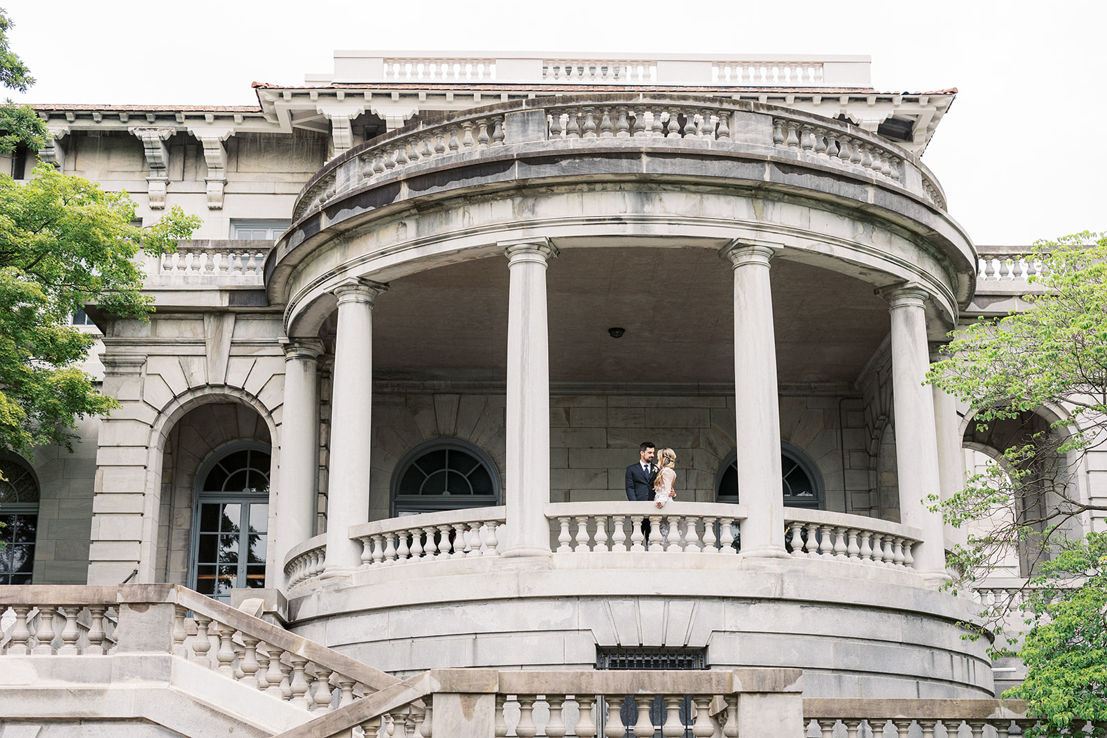 Newlyweds share a moment together on a large terrace overlooking the grounds of the Elkins Estate