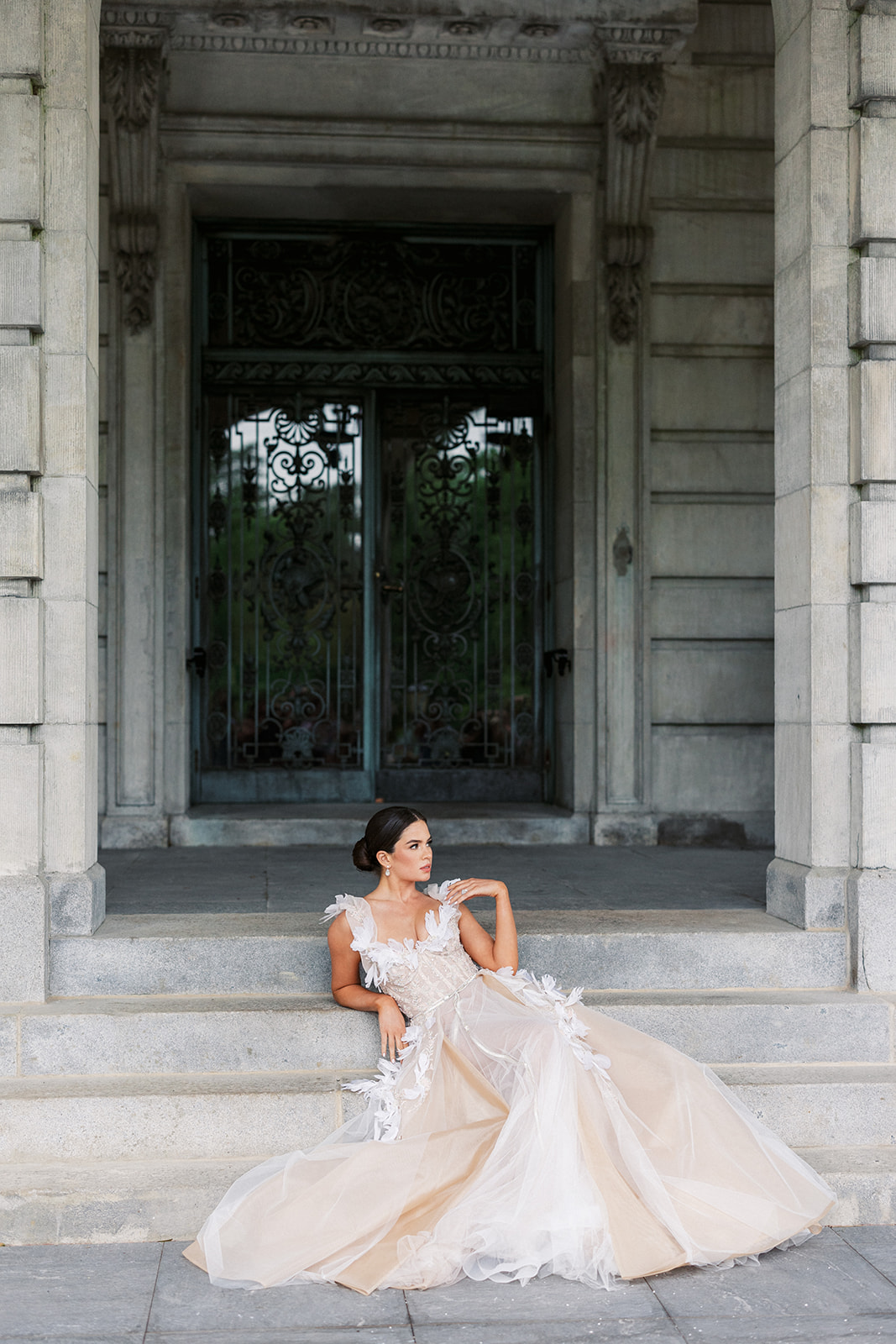 A bride sits and leans back on the steps to the entrance to the Elkins Estate
