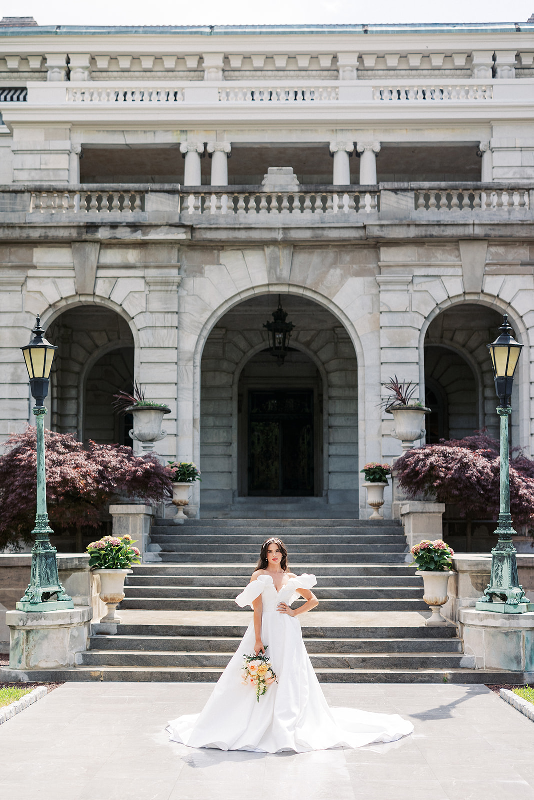 A bride rests a hand on her hip while standing at the front entrance to the luxurious Elkins Estate