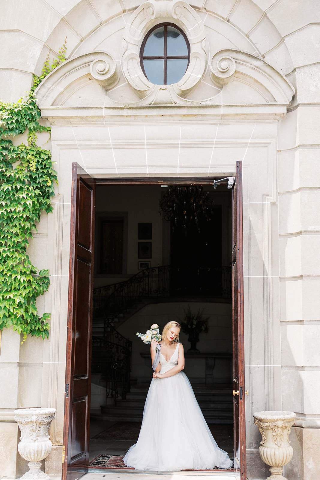 A bride stands in the large entrance to the Oheka Castle