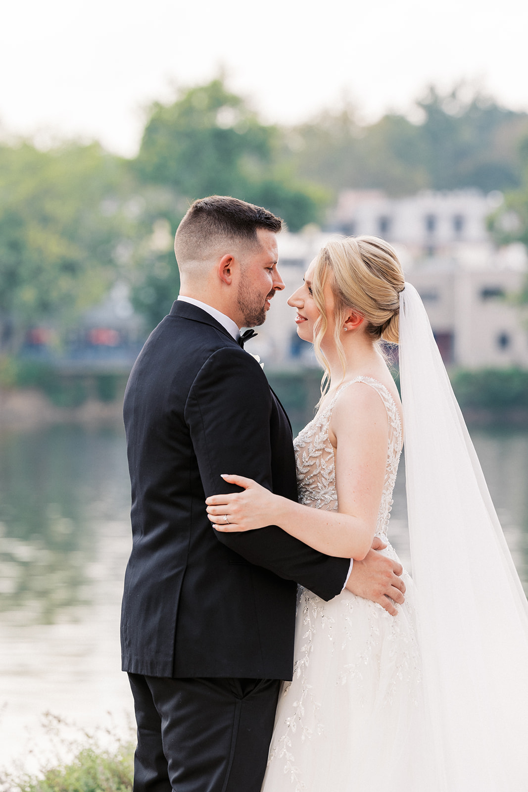 Newlyweds lean in for a kiss while hugging on the edge of a river