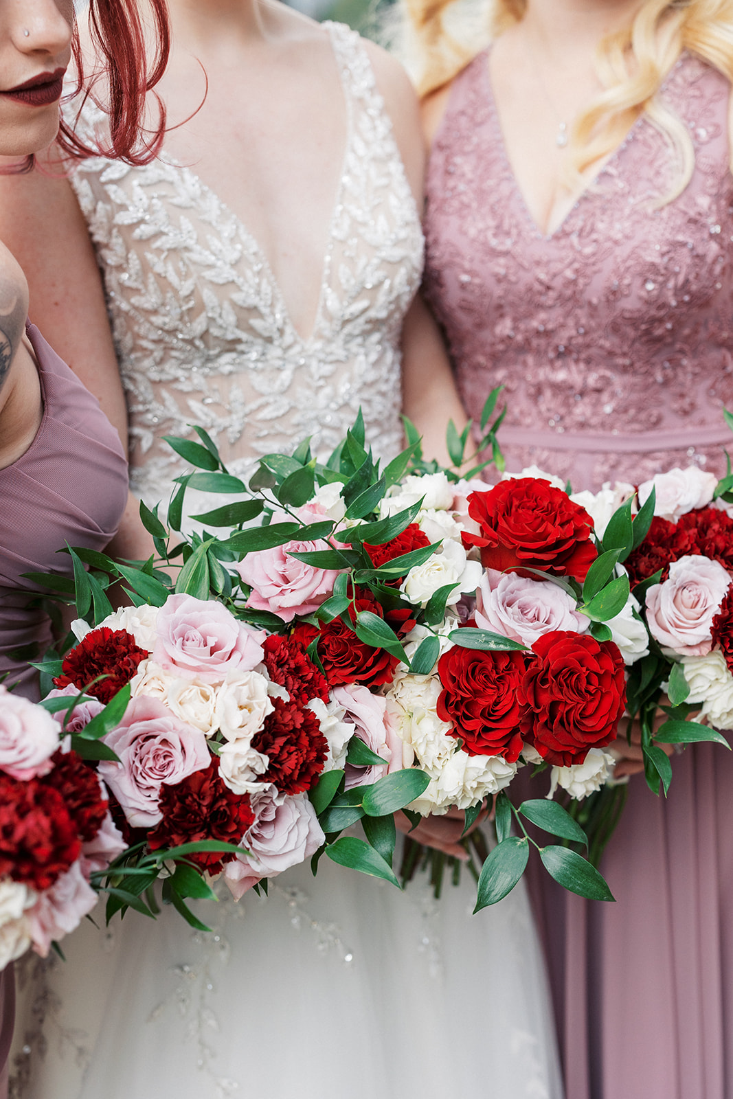 Details of a bride's red white and pink bouquet with her bridesmaids at a Lambertville Station Wedding