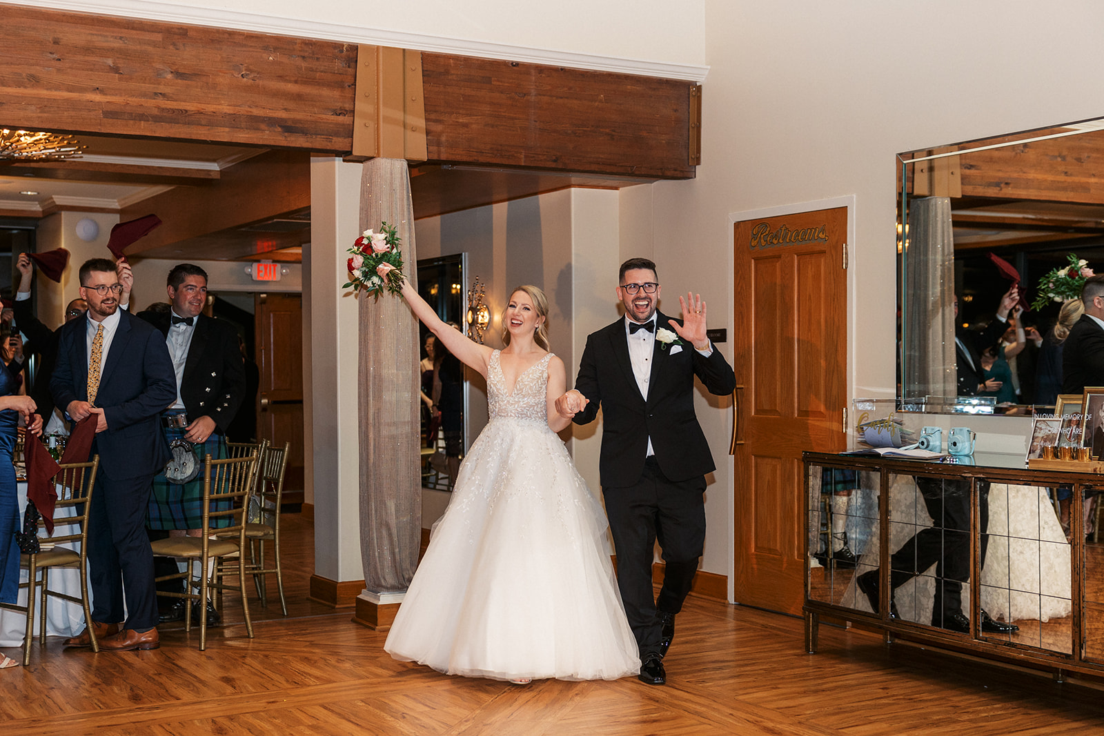 Newlyweds enter their wedding reception to cheers from guests