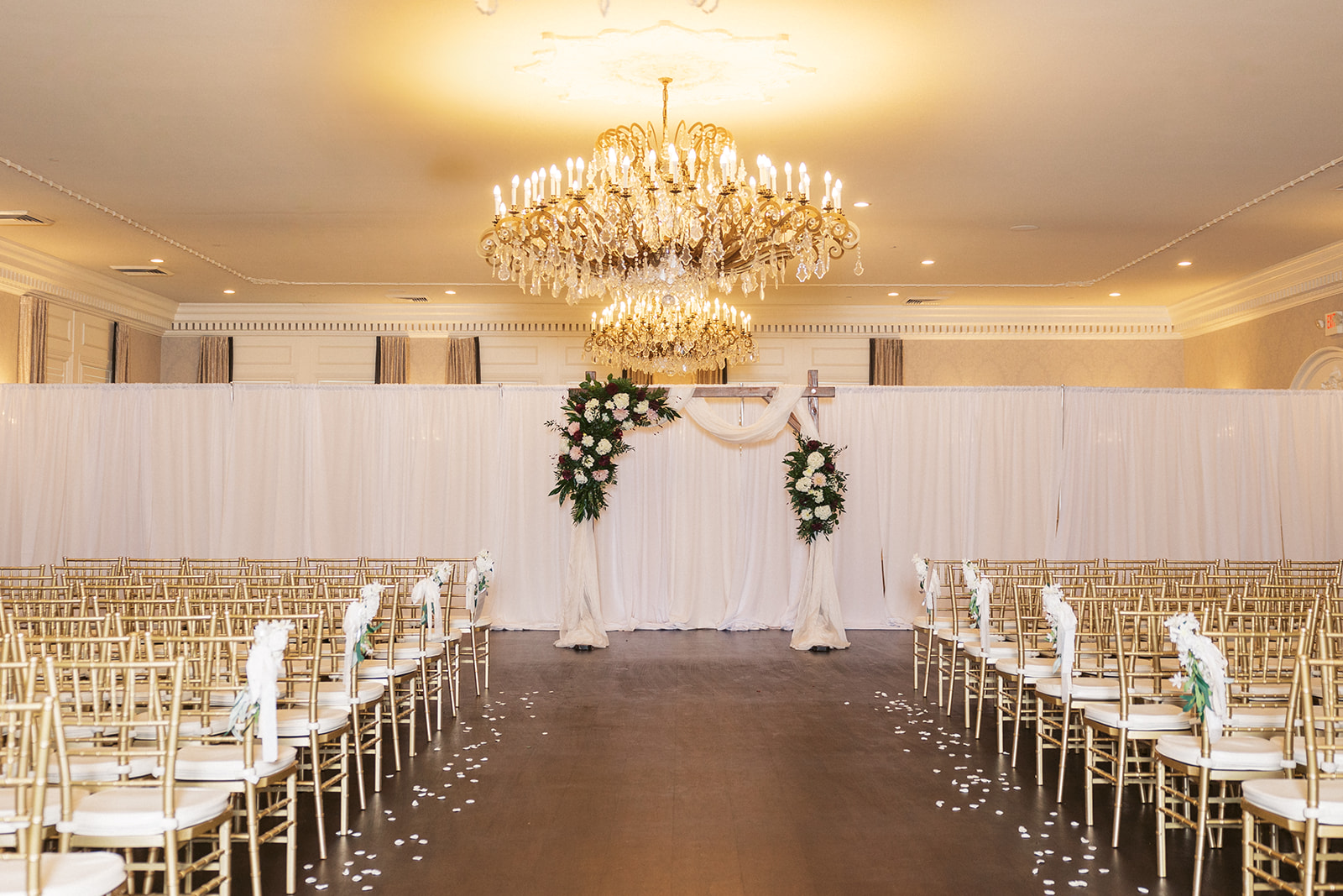 Details of a wedding ceremony set up with white drapes and a large chandelier at The Belle of Blue Bell