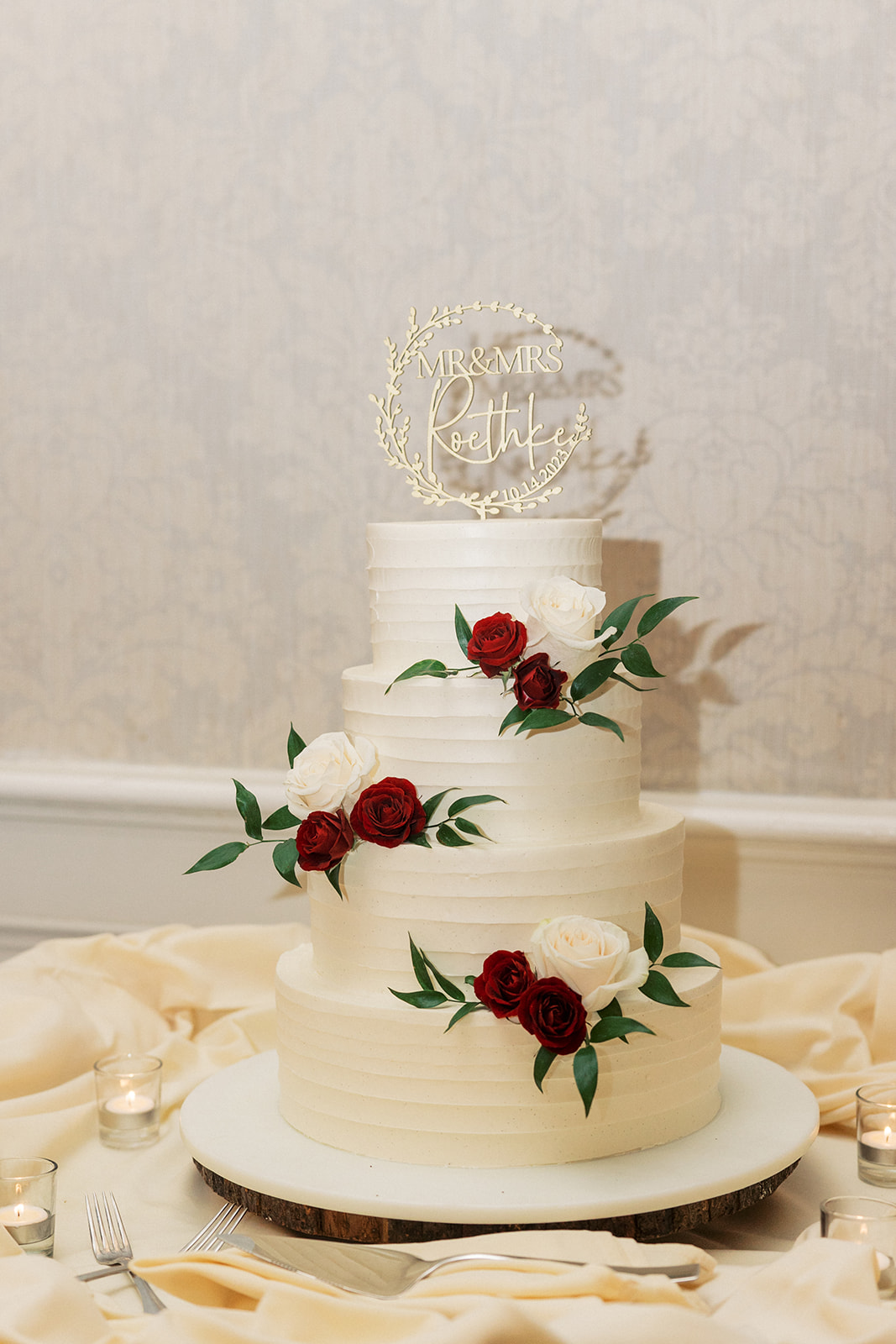 Details of a 4 tier wedding cake with red and white roses and custom topper