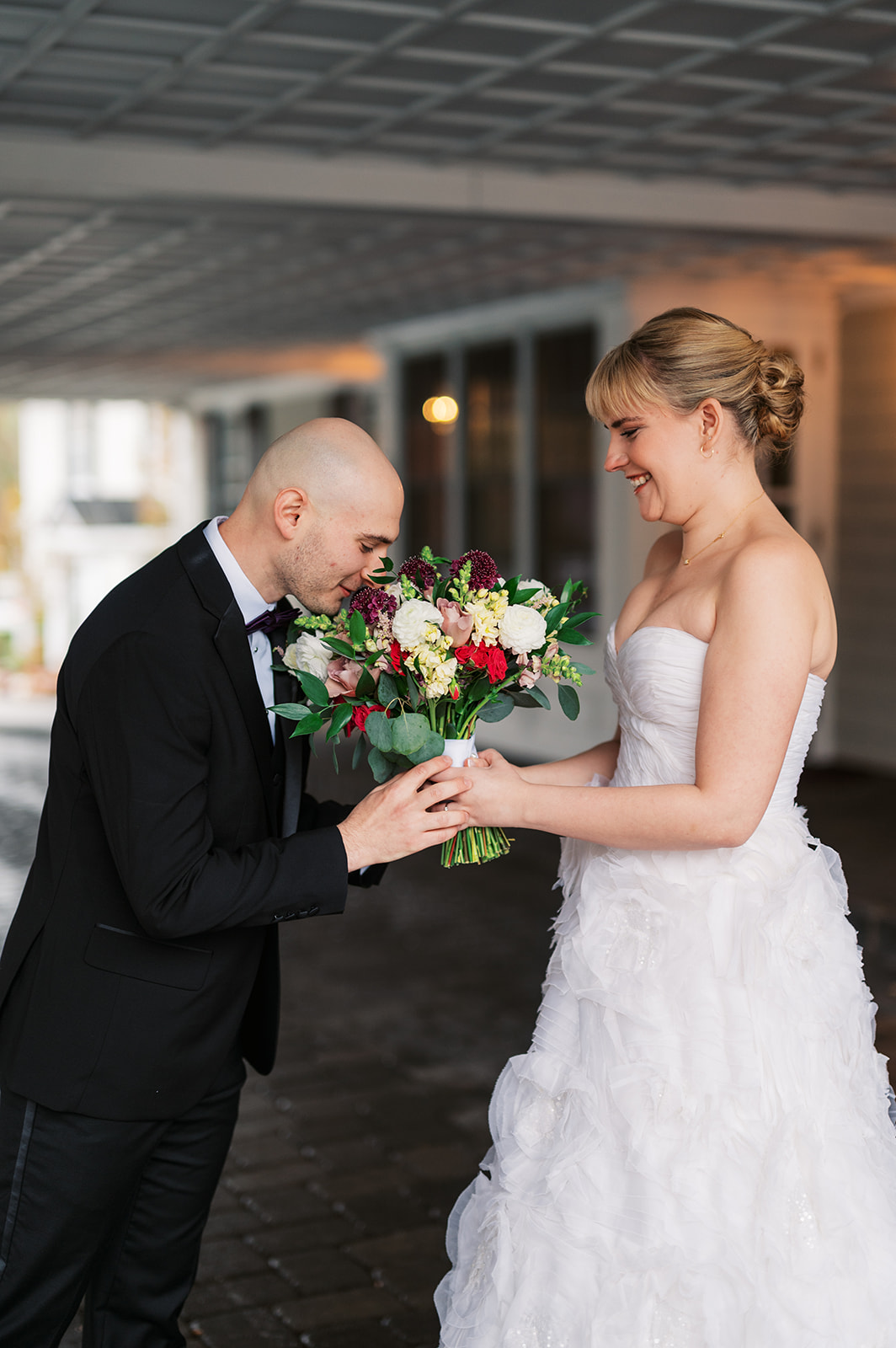 A groom smells his bride's flowers