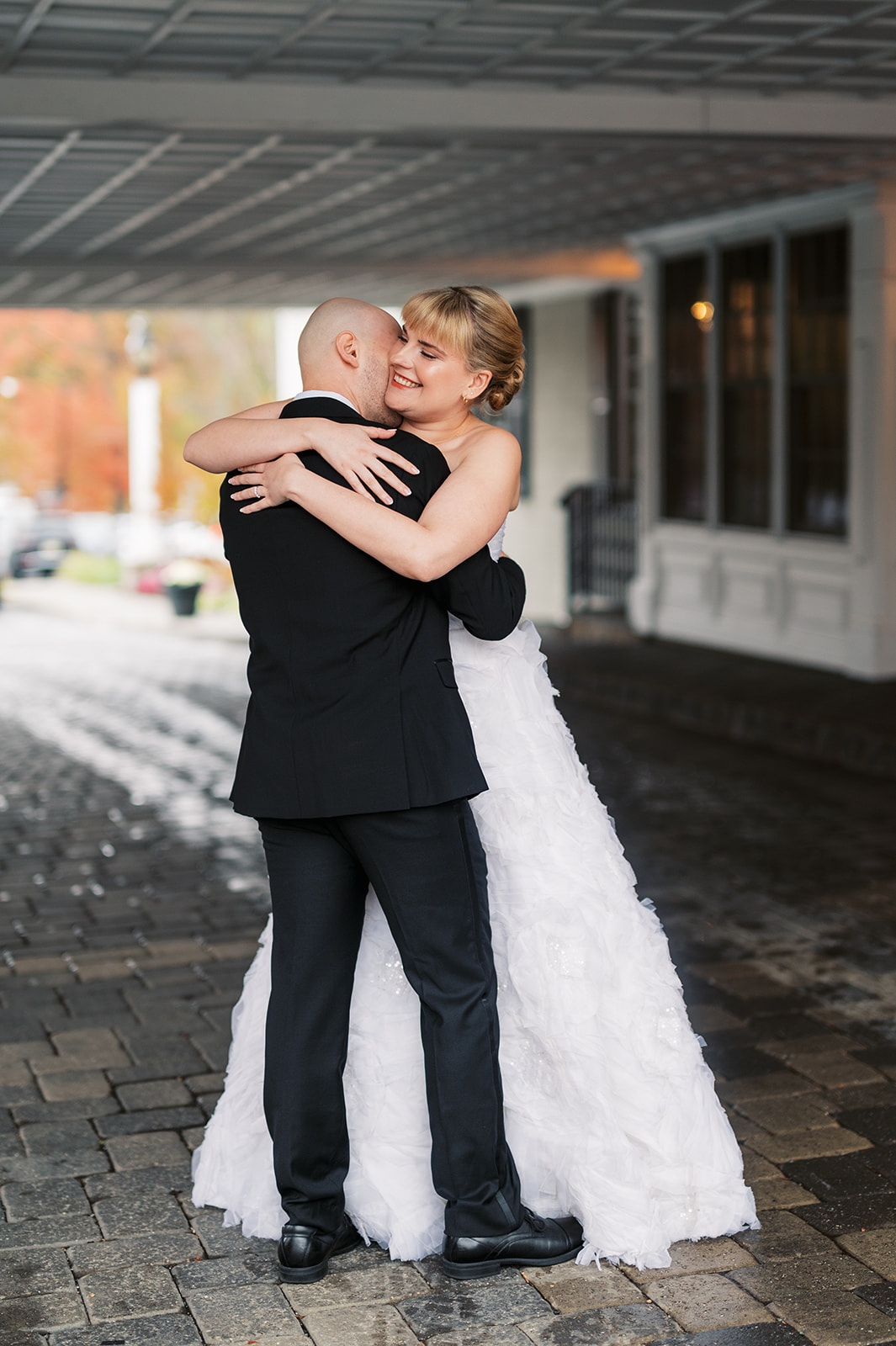 Newlyweds hug and smile while under drop off covering for their wedding
