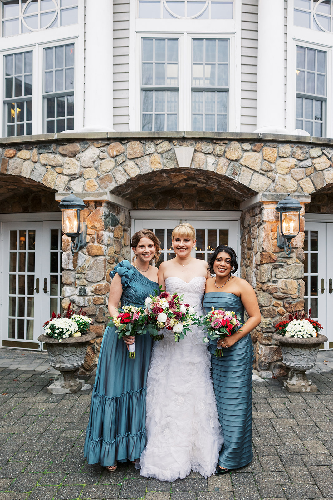 A bride stands with her bridesmaids outside the Olde Mill Inn Wedding venue