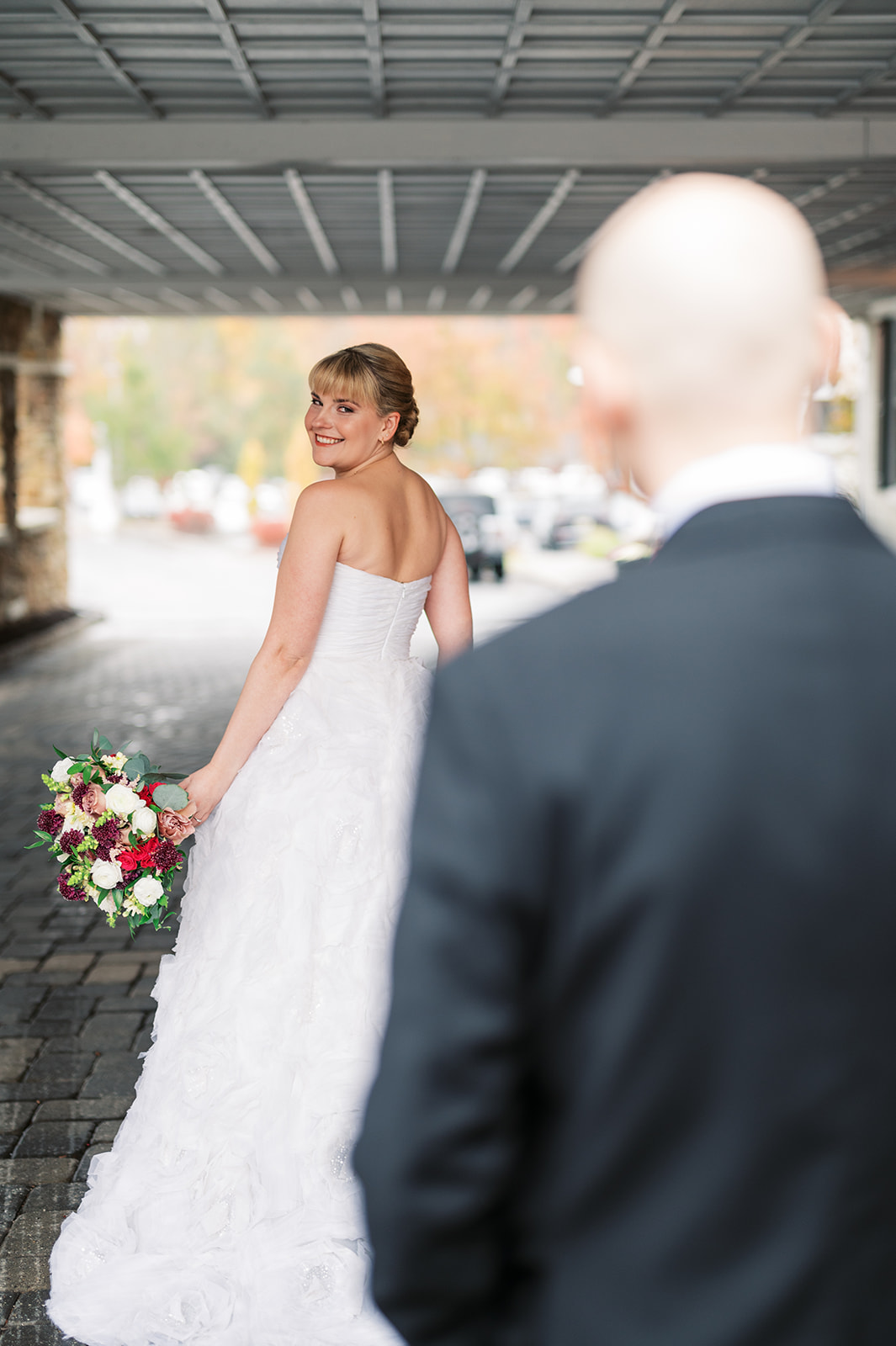 A bride looks over her shoulder during her first look while showing her dress to her groom Olde Mill Inn Wedding