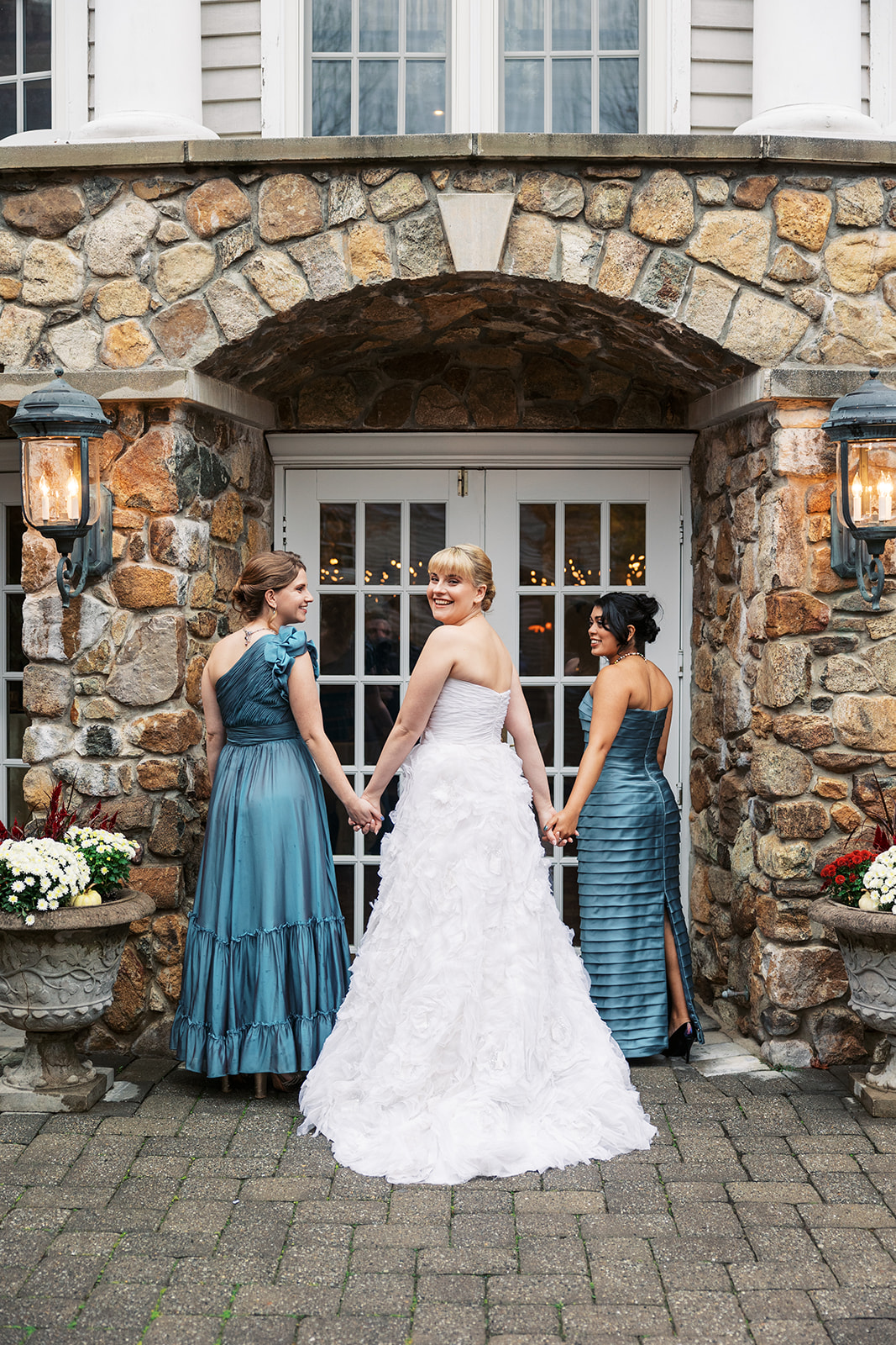 A bride holds hands with her bridesmaids while walking into her reception venue Olde Mill Inn Wedding