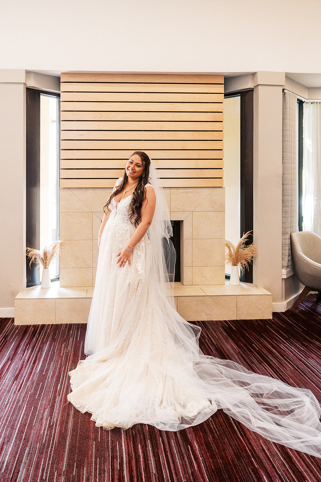 A bride displays her long train and veil in a hotel room while getting ready