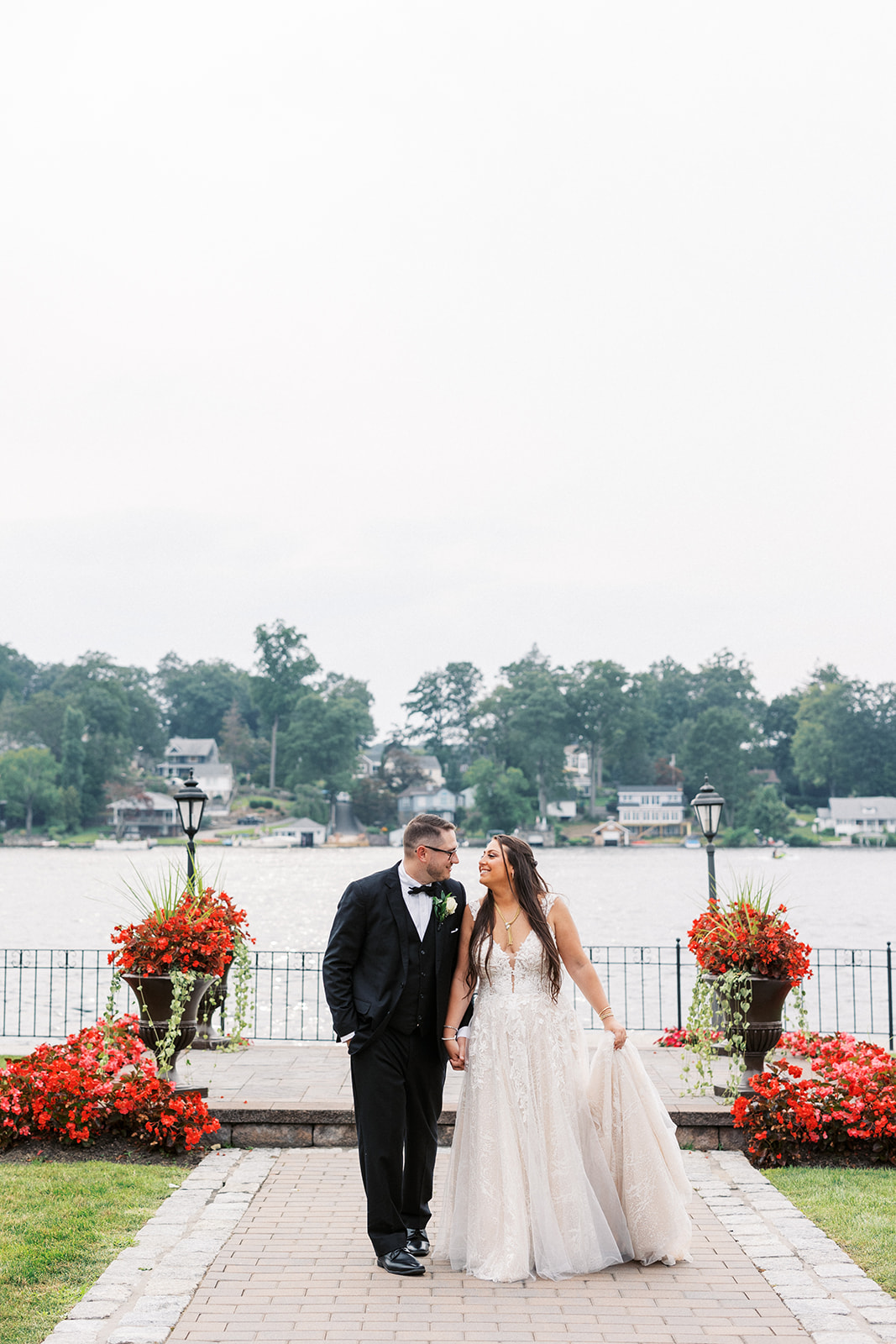 Newlyweds walk up a brick sidewalk by the water at the Villa Barone Hilltop Manor