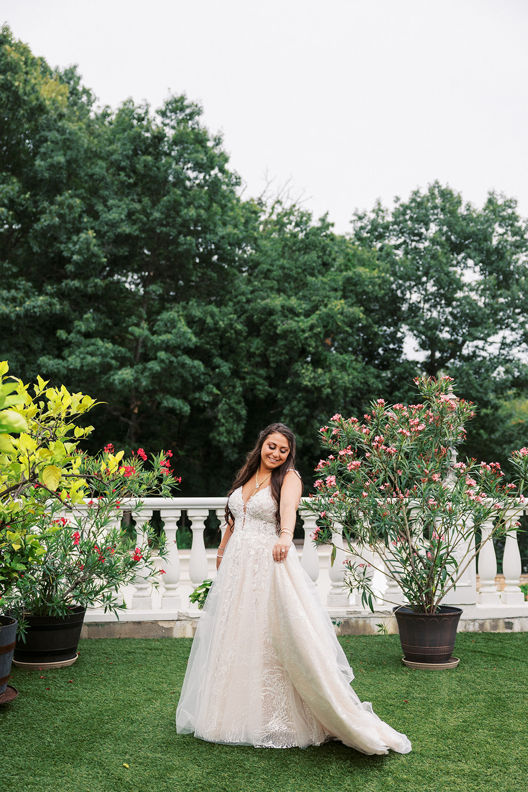 A bride twirls by herself with her dress on a garden terrace