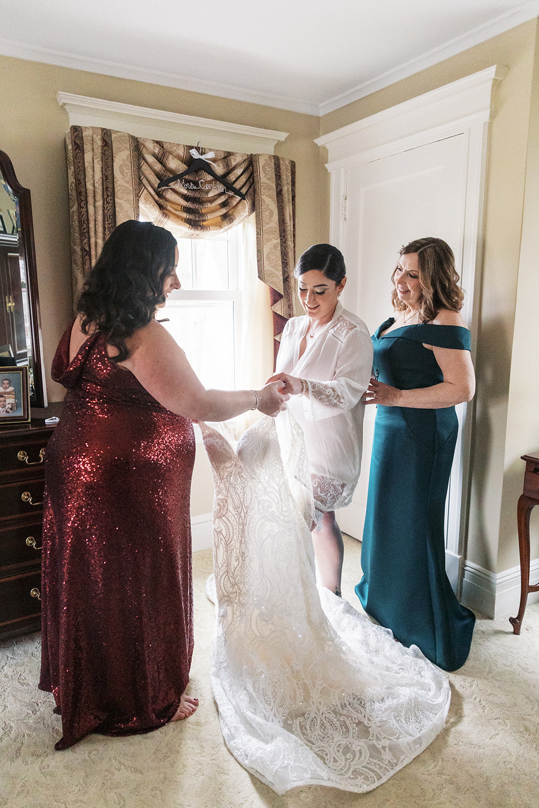 A bride steps into her dress with help from mom
