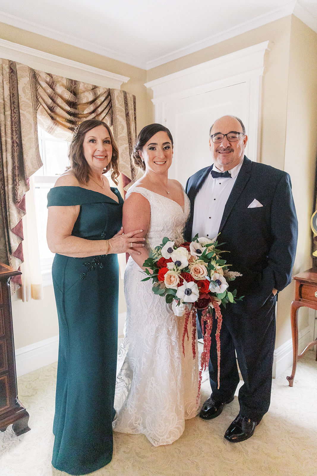 A bride stands with mom and dad in the getting ready room