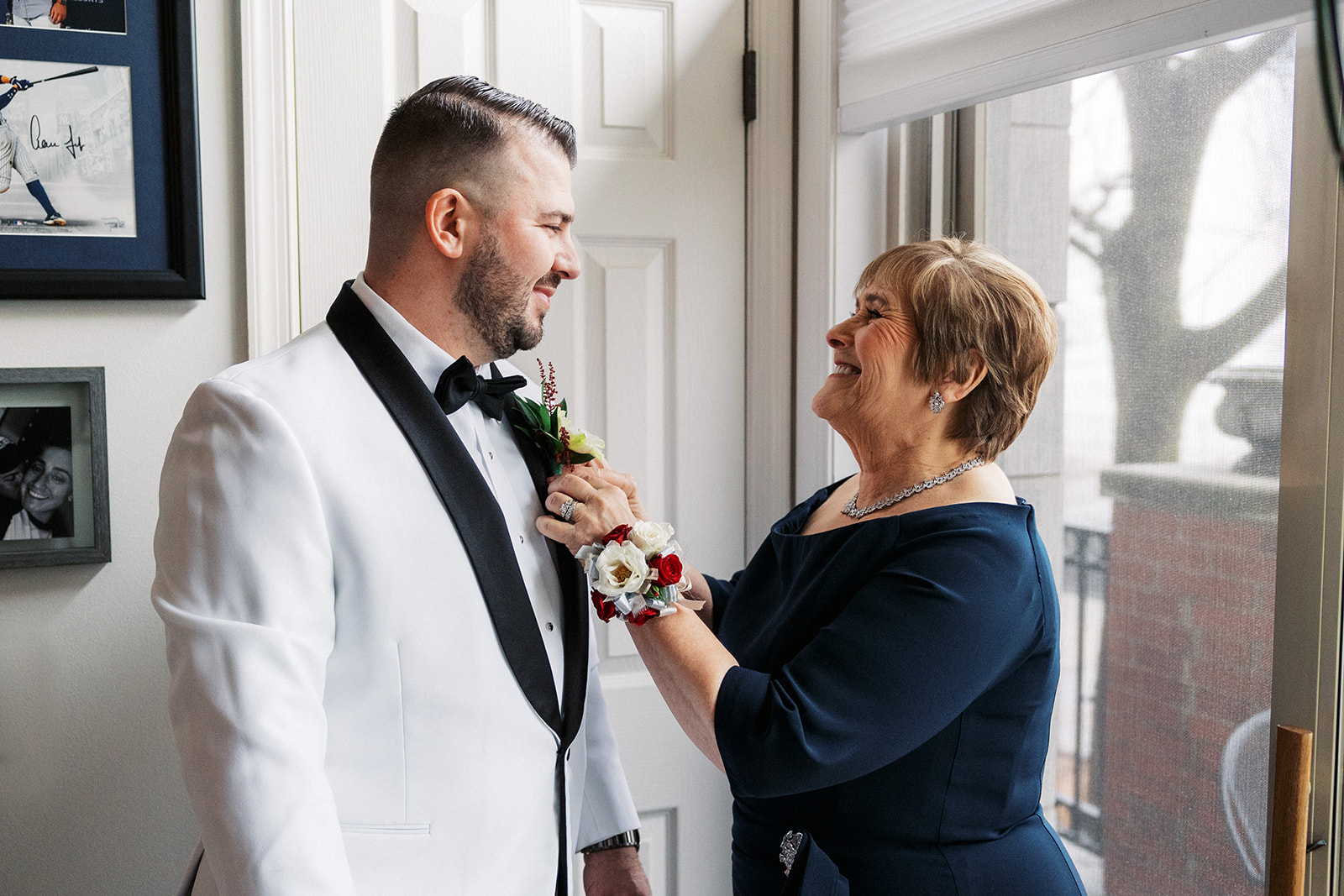 A happy mother pins the boutonniere on her sons wedding tuxedo