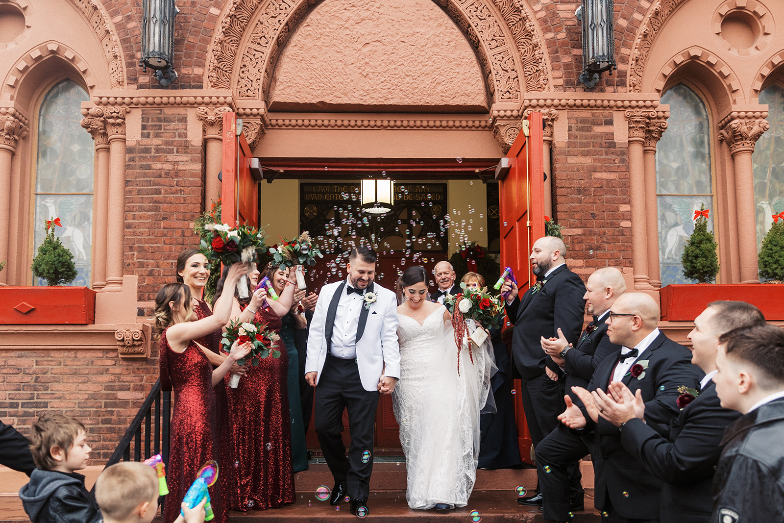 Newlyweds exit their wedding ceremony with guests on either side of stairs and bubbles at their Above Weddings