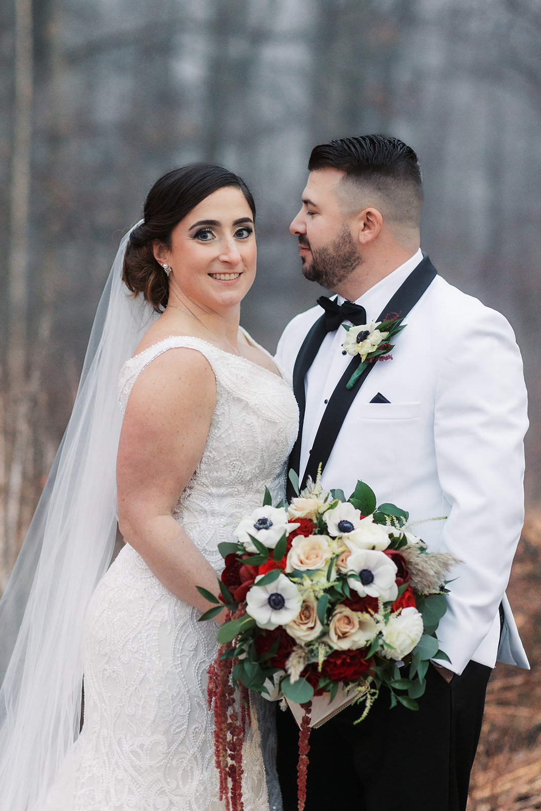 Newlyweds stand together outside in a lace dress and white/black tuxedo at their Above Weddings