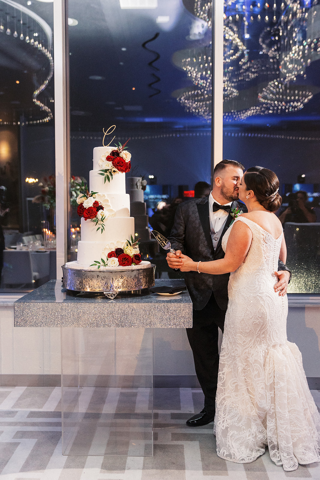 Newlyweds kiss while cutting their 5 tier cake at their Above Weddings