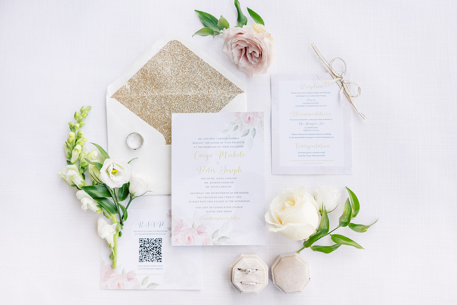 Details of wedding invitations and rings on a white table