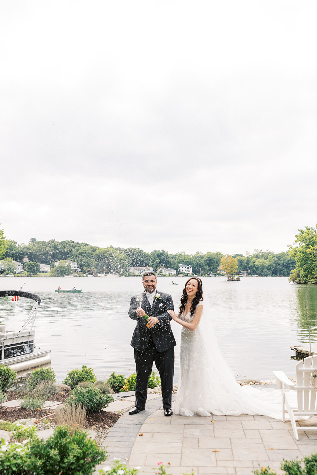 Newlyweds pop a bottle of champagne on a waterfront patio at their Seasons Catering Wedding