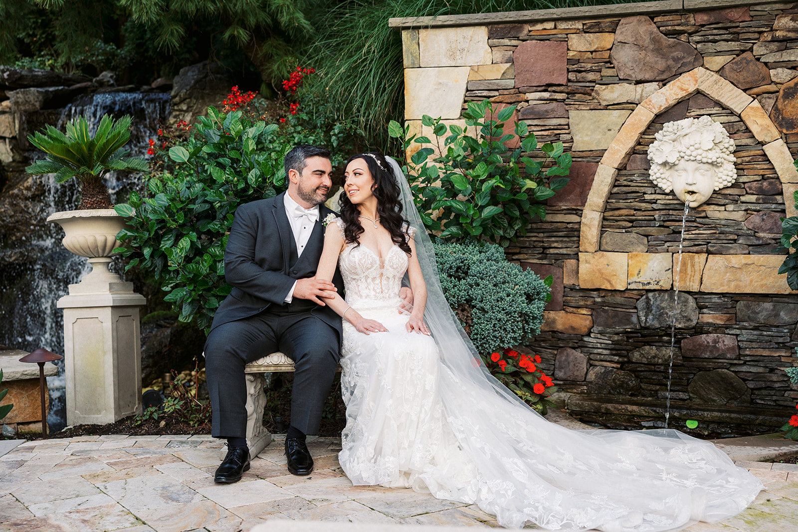 Newlyweds sit on a garden bench by a fountain at their Seasons Catering Wedding