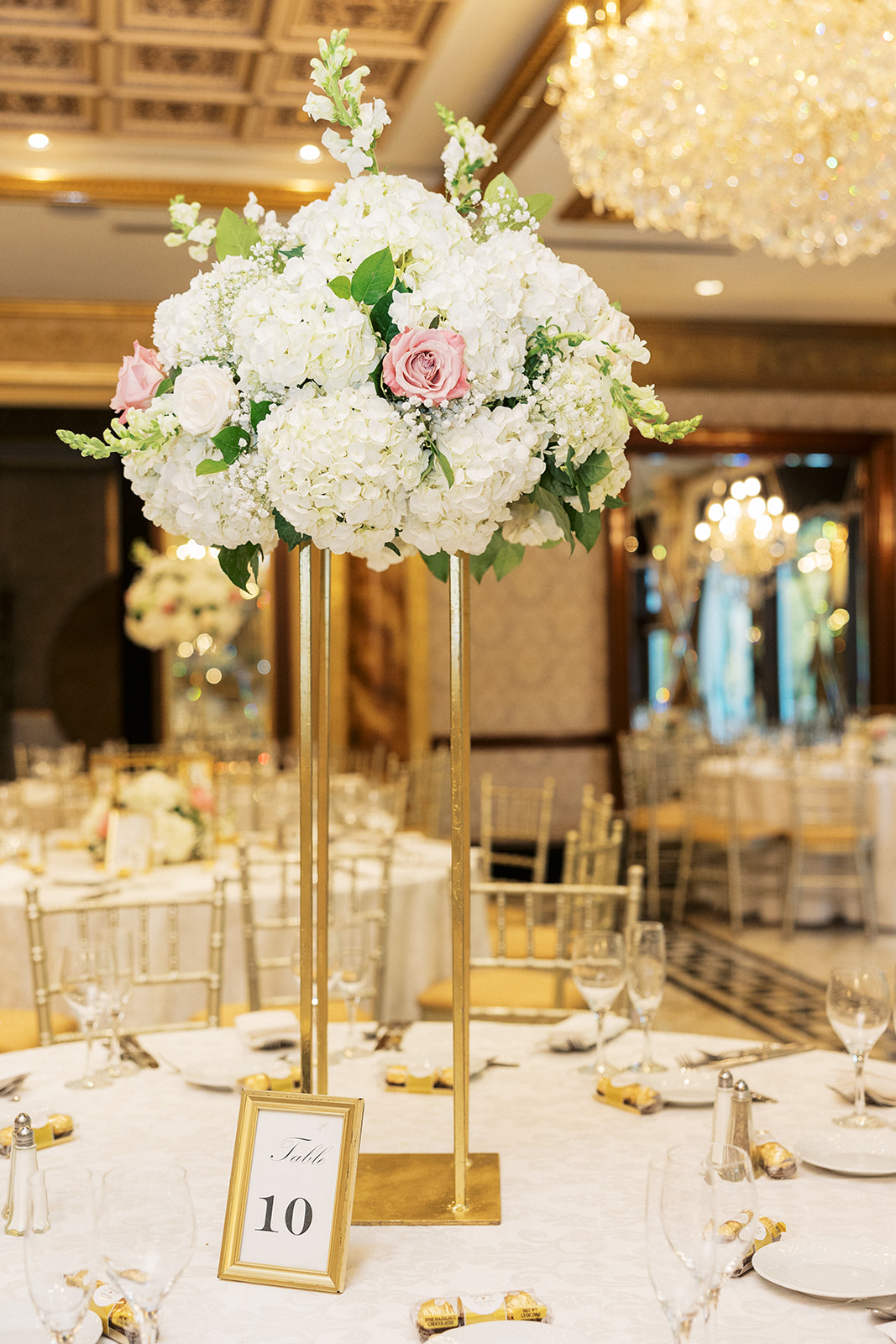 Details of a table setting center piece with gold hardware and white and pink flowers