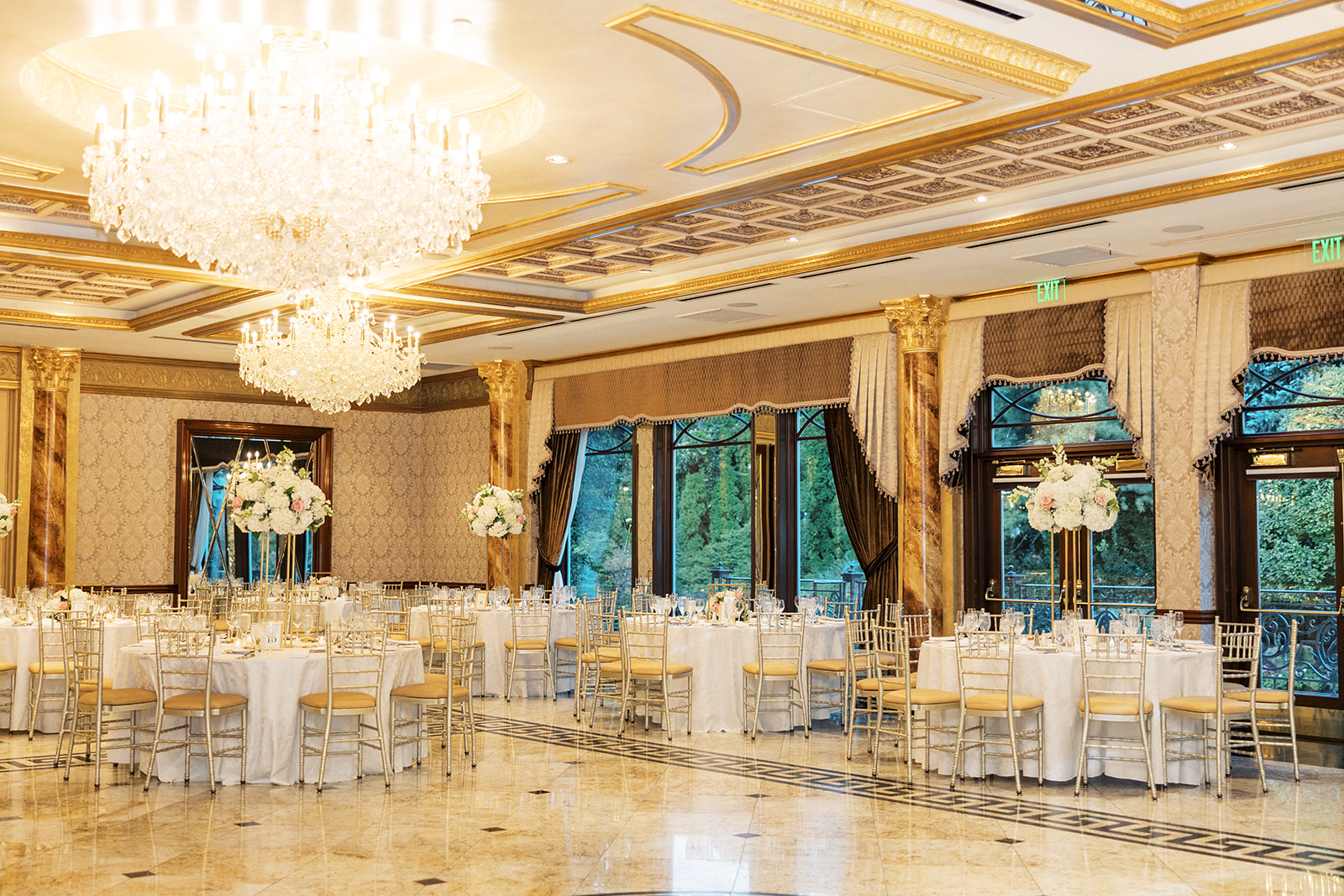 A look into the ornate Seasons Catering Wedding reception hall with tables set up and crystal chandeliers