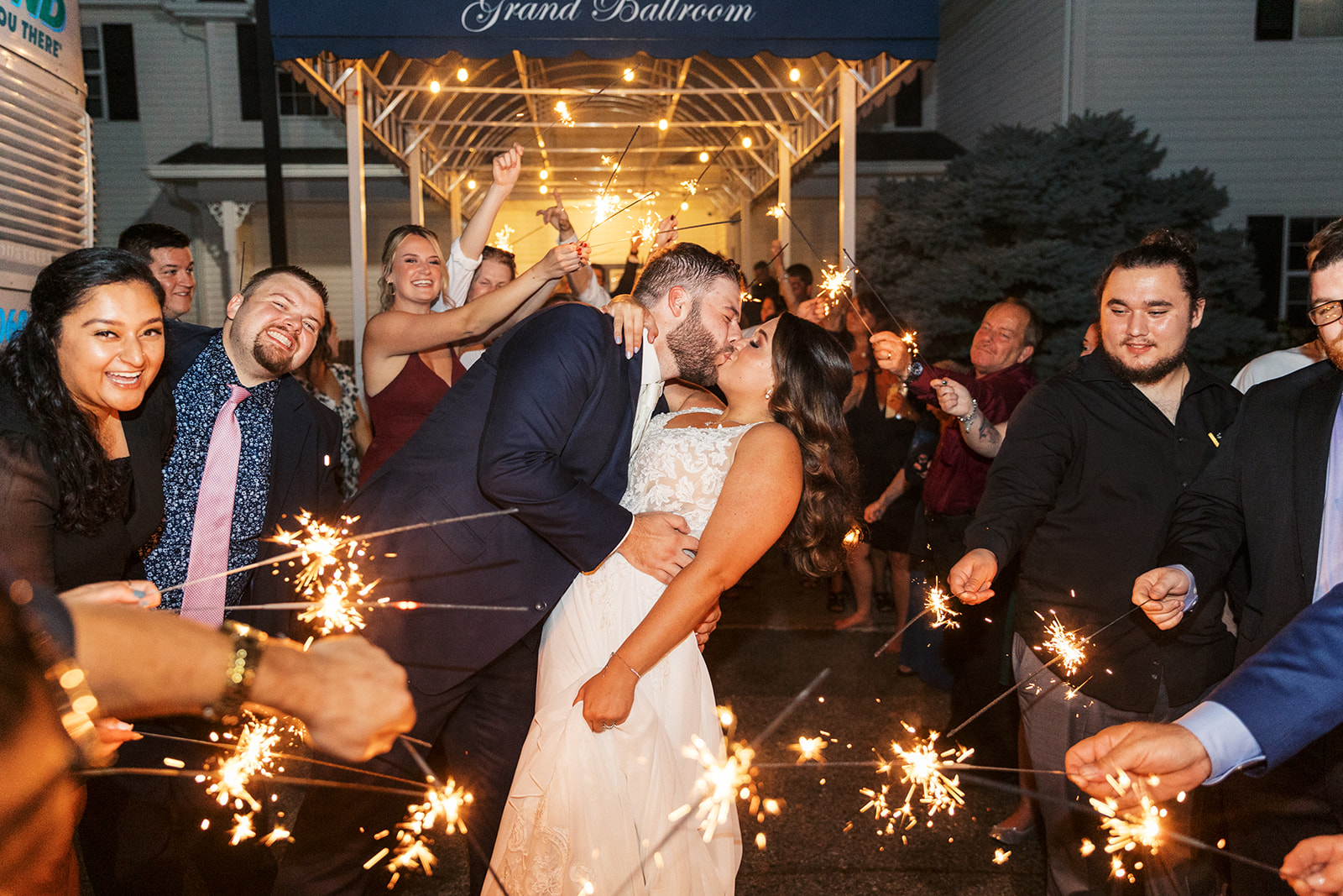 Newlyweds kiss while surrounded by their guests holding sparklers while exiting their Skyview Golf Club Wedding