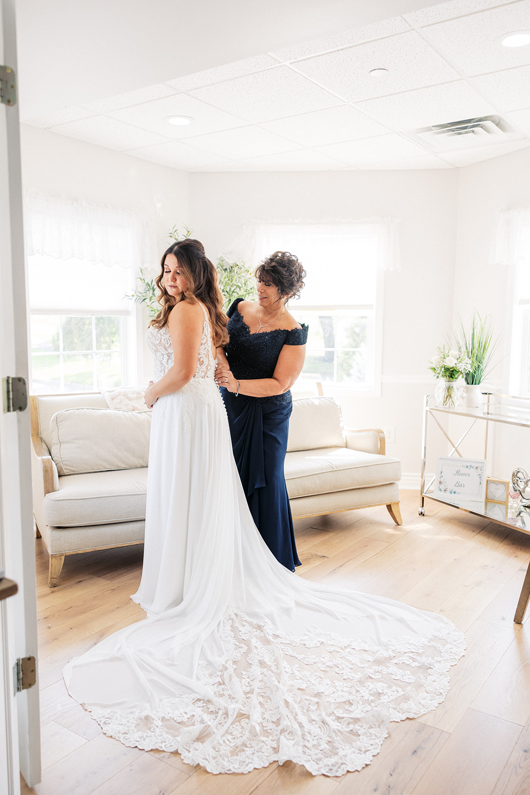 A mother in a dark dress helps her daughter put on her wedding dress