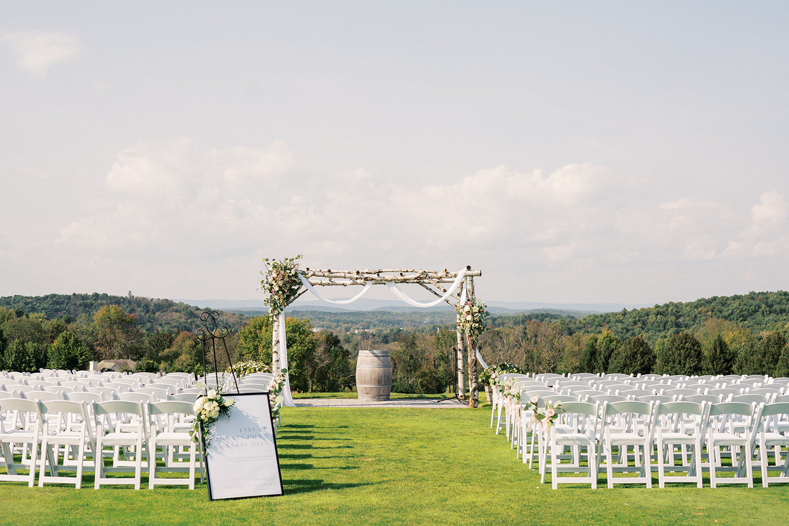A wedding ceremony set up with white chairs and aspen arbor on the top of a hill at a Skyview Golf Club Wedding