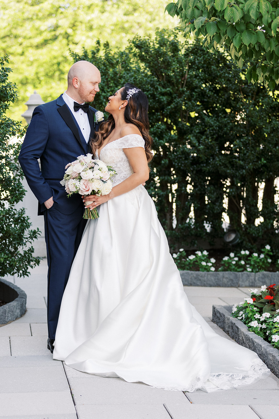 Newlyweds stand together in a garden smiling at each other at their The Palace At Somerset Wedding