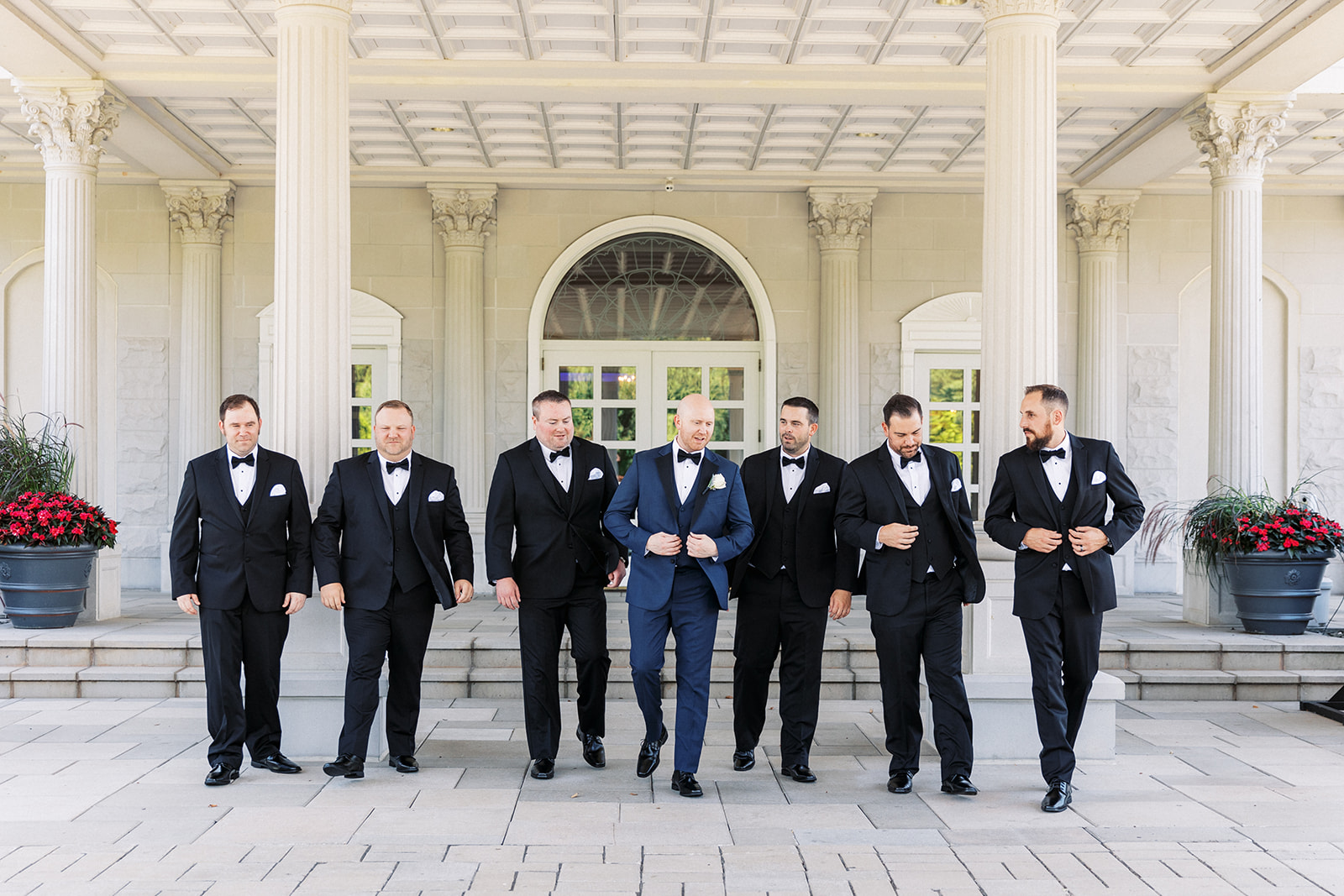 A groom walks with his 6 groomsmen through an ornate car port at his The Palace At Somerset Wedding