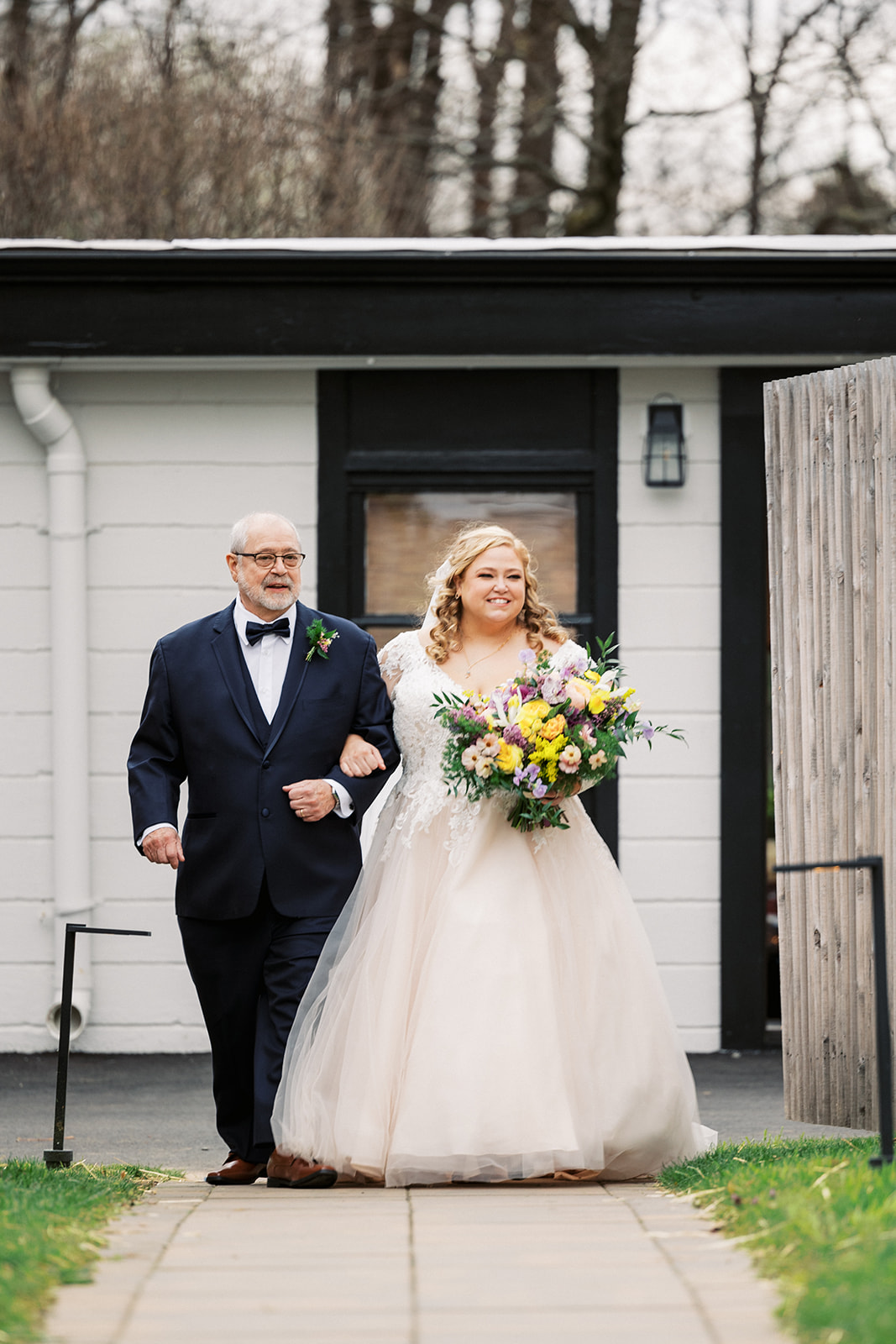 A father walks his bride down the aisle to her outdoor wedding ceremony