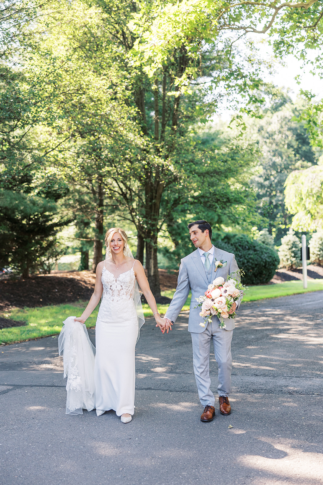 Newlyweds hold hands while walking down a shady street at their Pen Ryn Estate Wedding