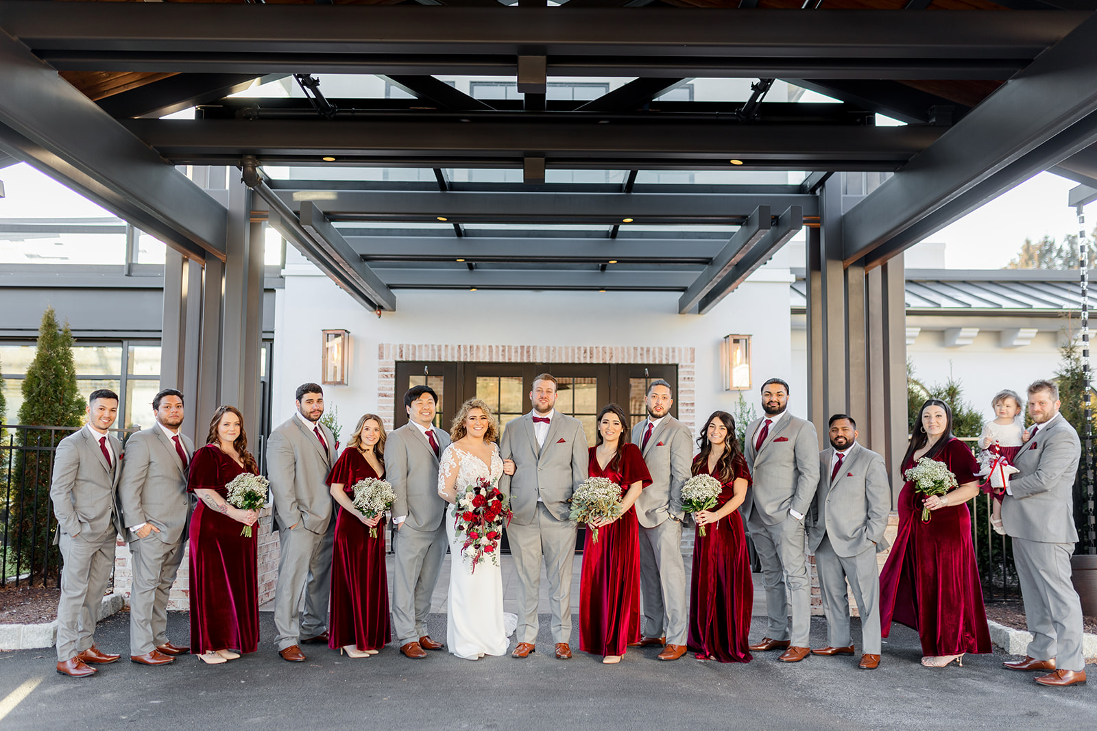 Newlyweds stand in line with their large wedding party under a covered driveway entrance