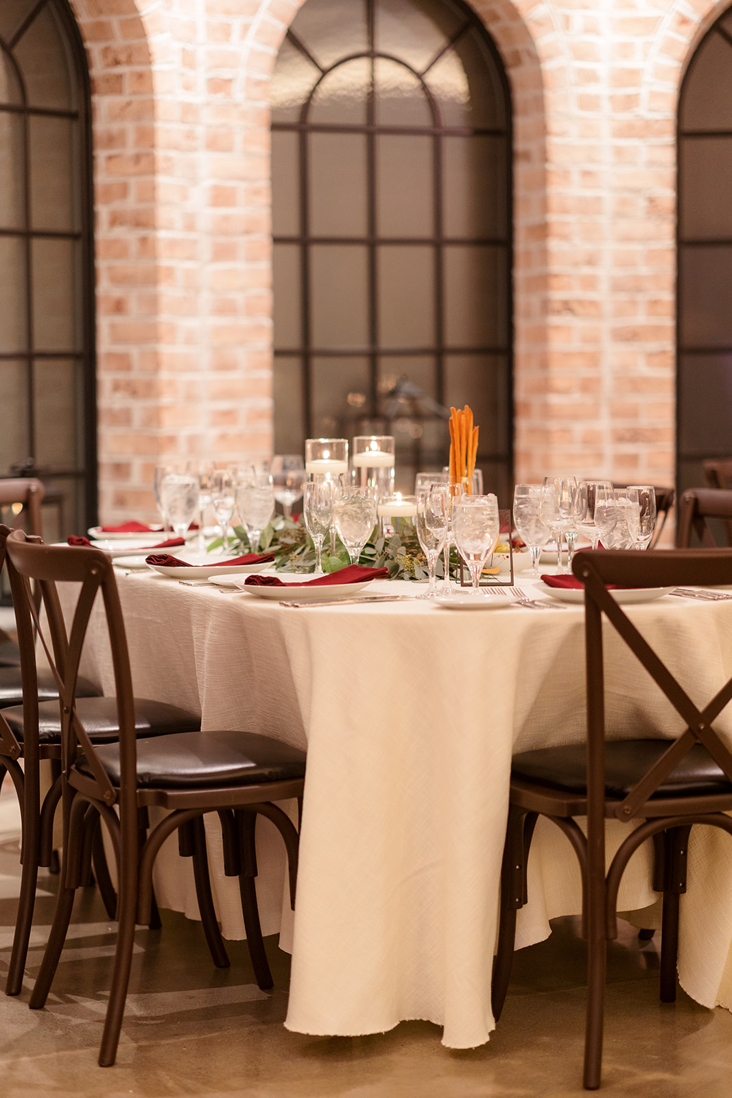 Details of a white linen dressed table with red napkins at The Refinery At Perona Farms