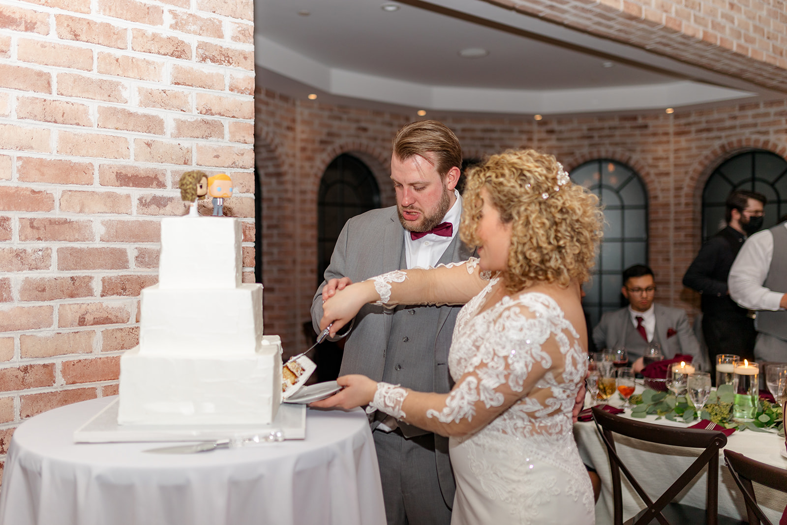 Newlyweds cut their cake together in a brick walled room at their The Refinery At Perona Farms wedding