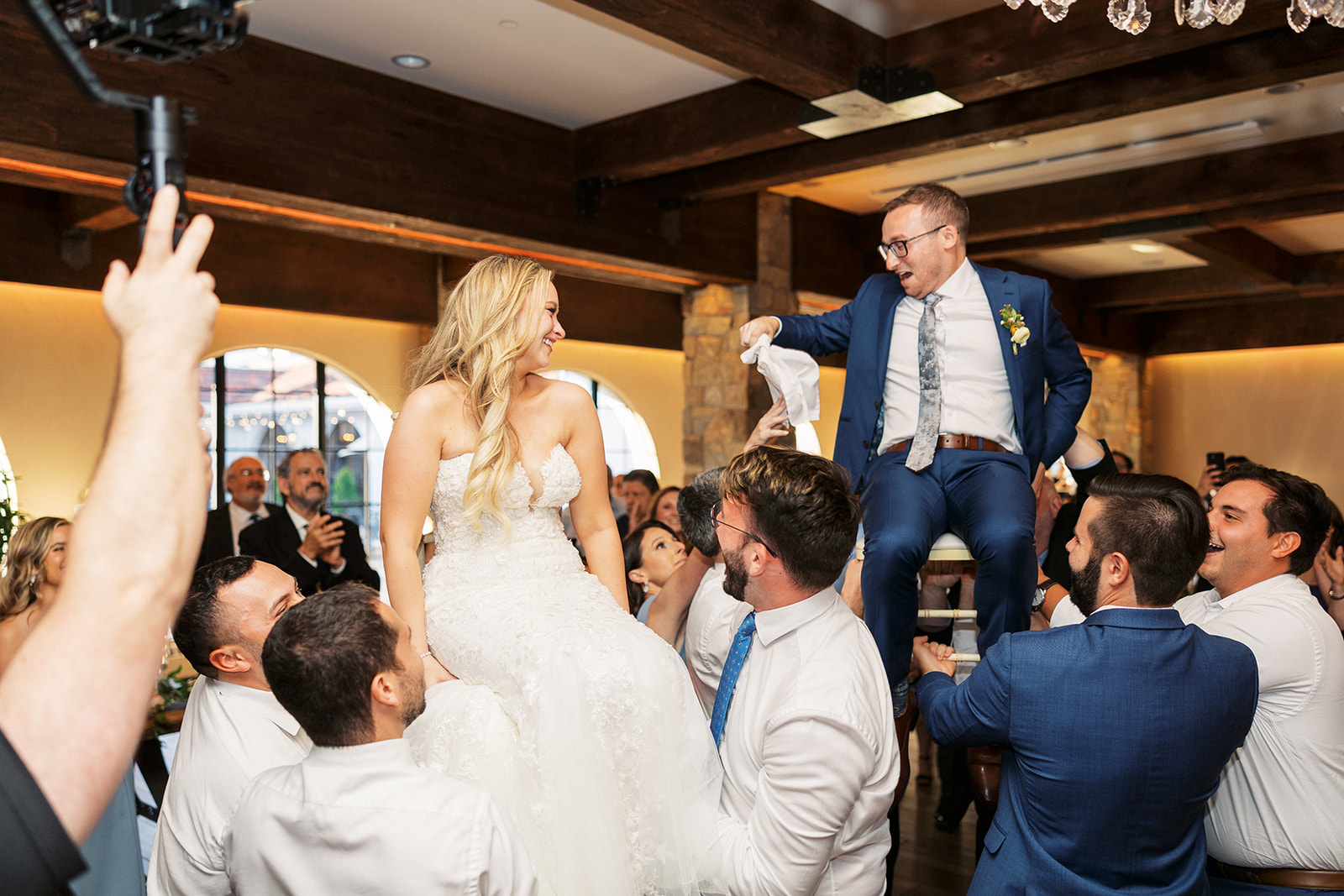 A bride and groom are lifted while sitting on chairs at their The Reserve At Perona Farms wedding reception