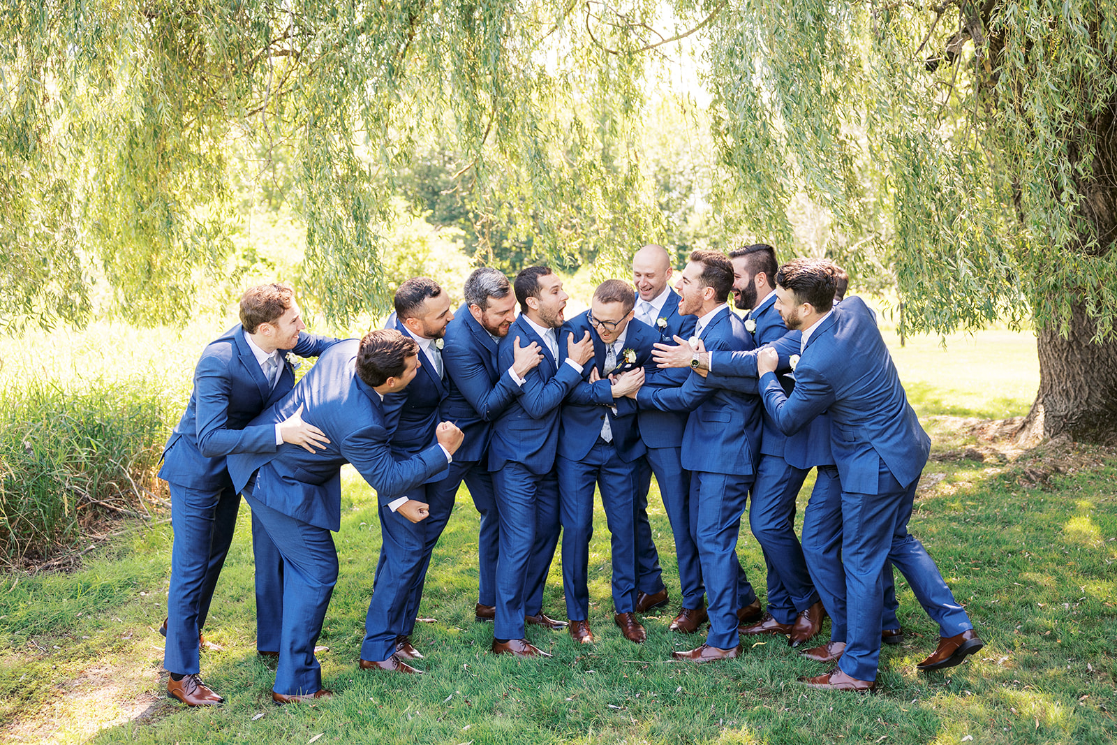 A groom is attacked by his groomsmen in blue suits at a The Reserve At Perona Farms