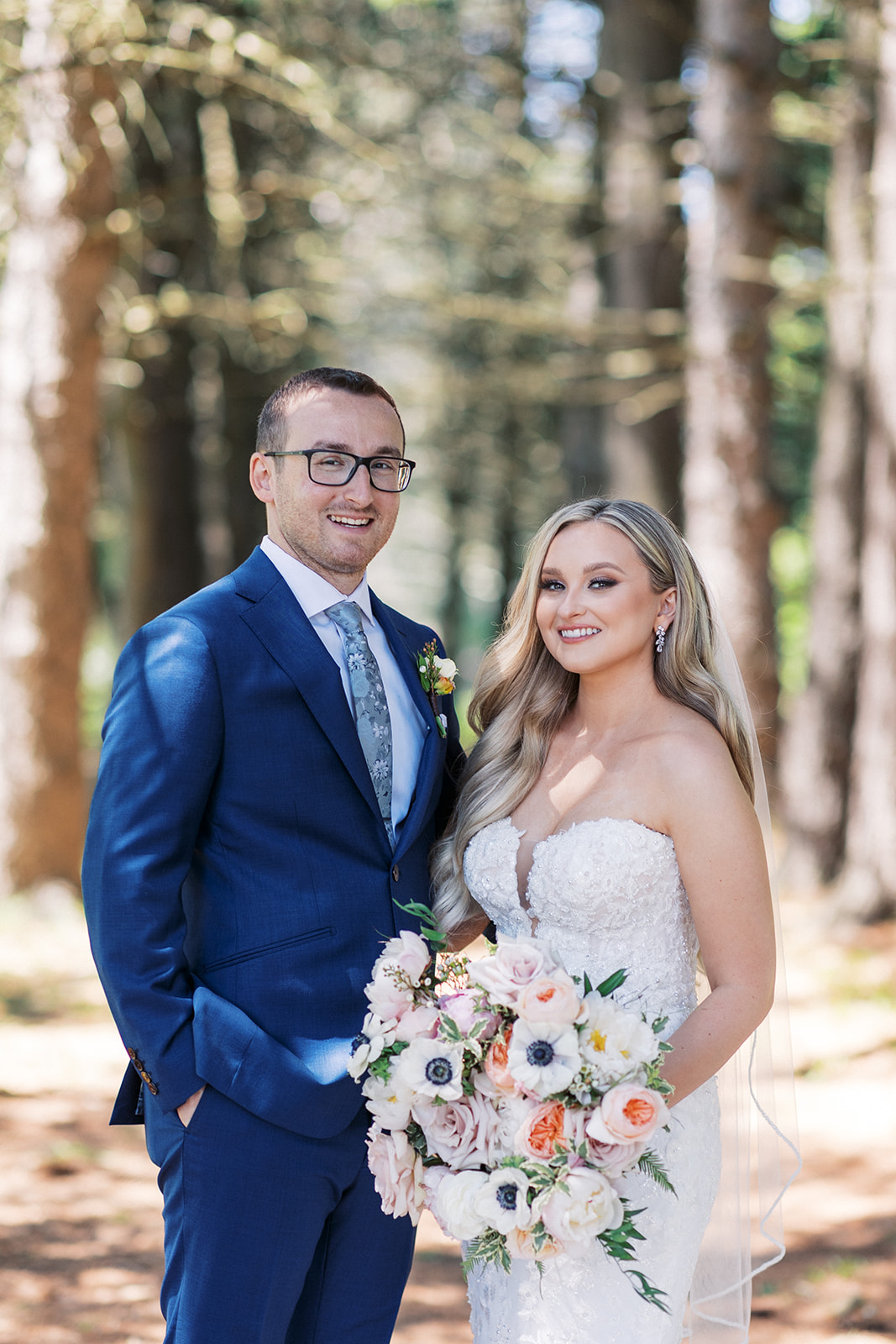 Newlyweds stand together and smile in a forest at their wedding