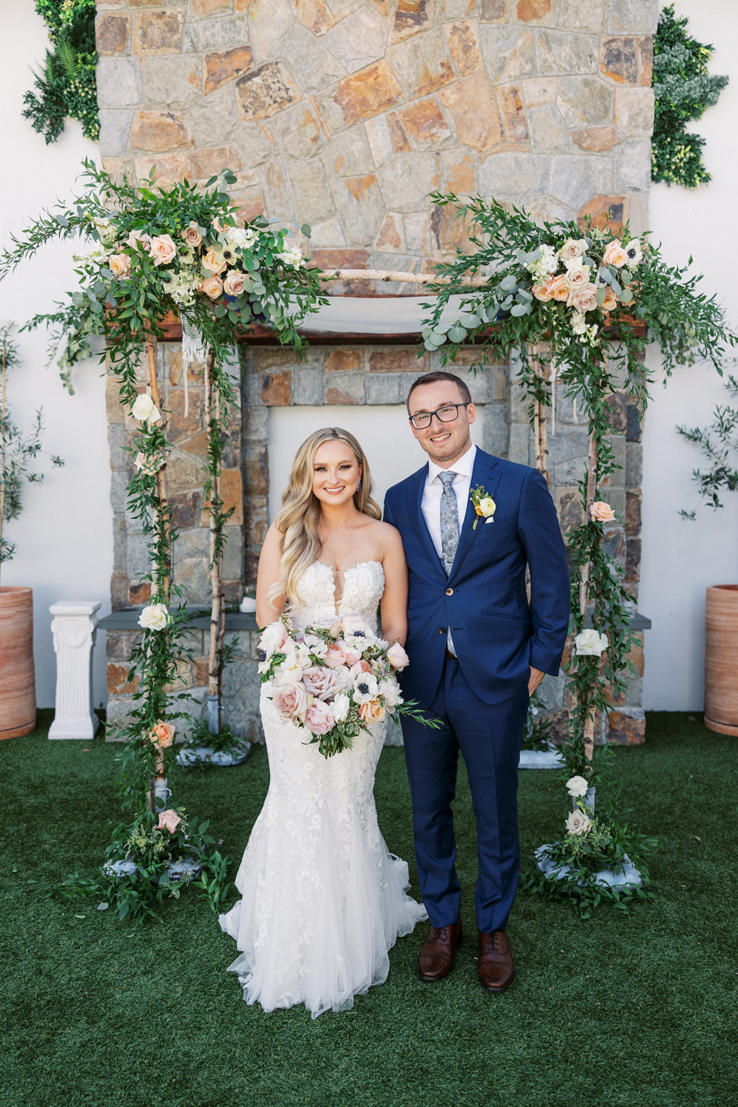 Newlyweds stand together under their floral arbor at The Reserve At Perona Farms wedding ceremony venue